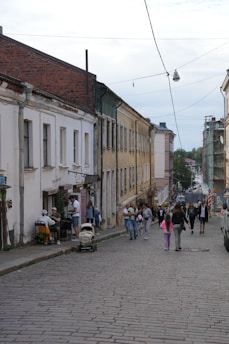 A group of people walking down a street next to tall buildings