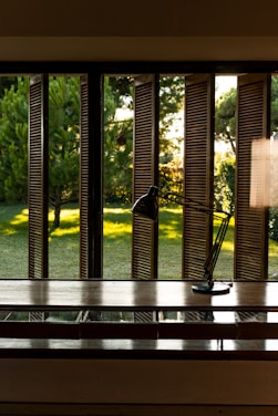 A desk with a lamp on it in front of a window