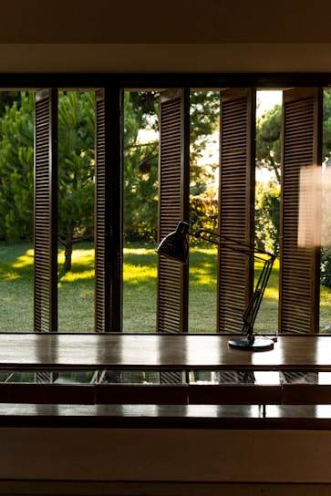 A desk with a lamp on it in front of a window
