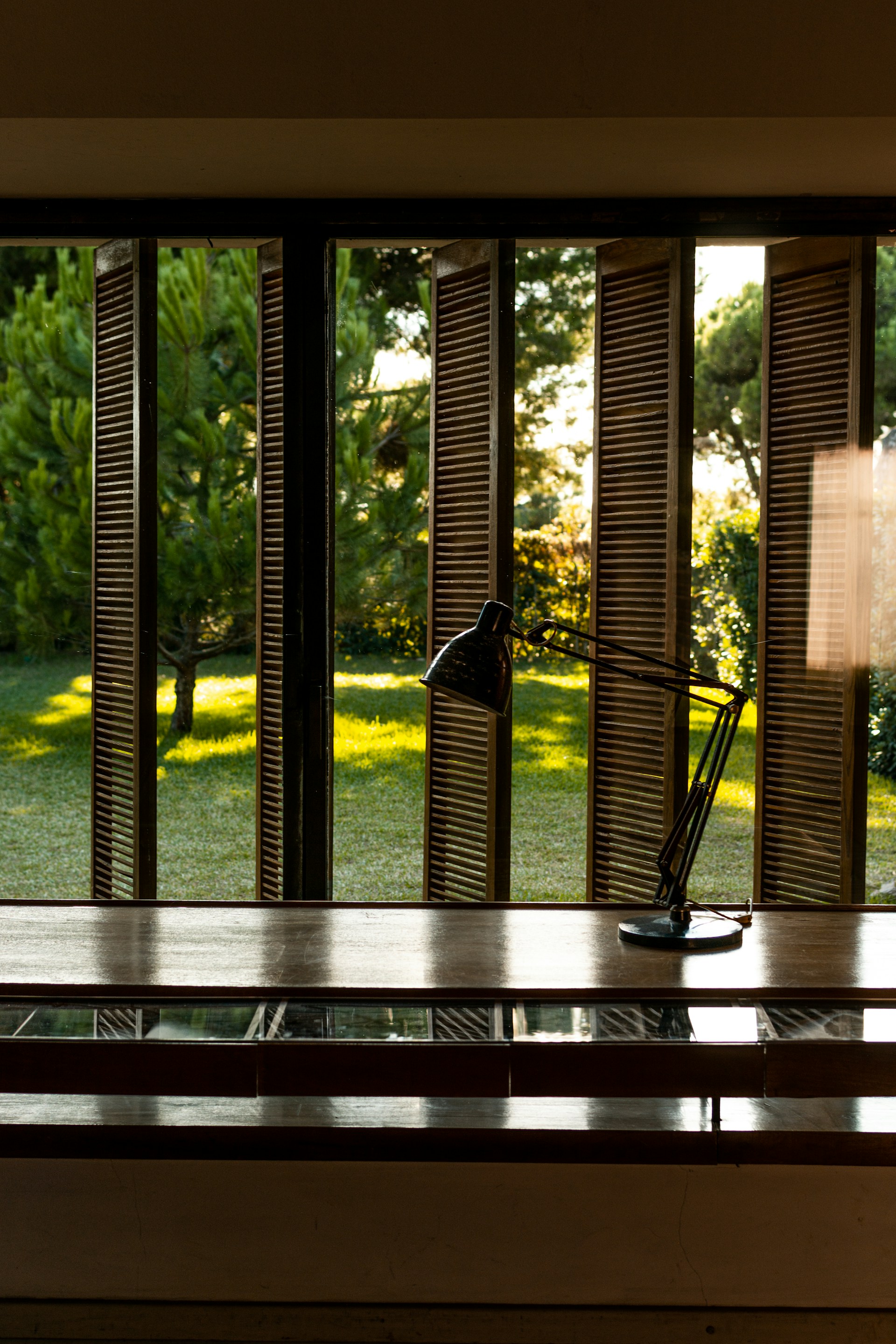 A desk with a lamp on it in front of a window