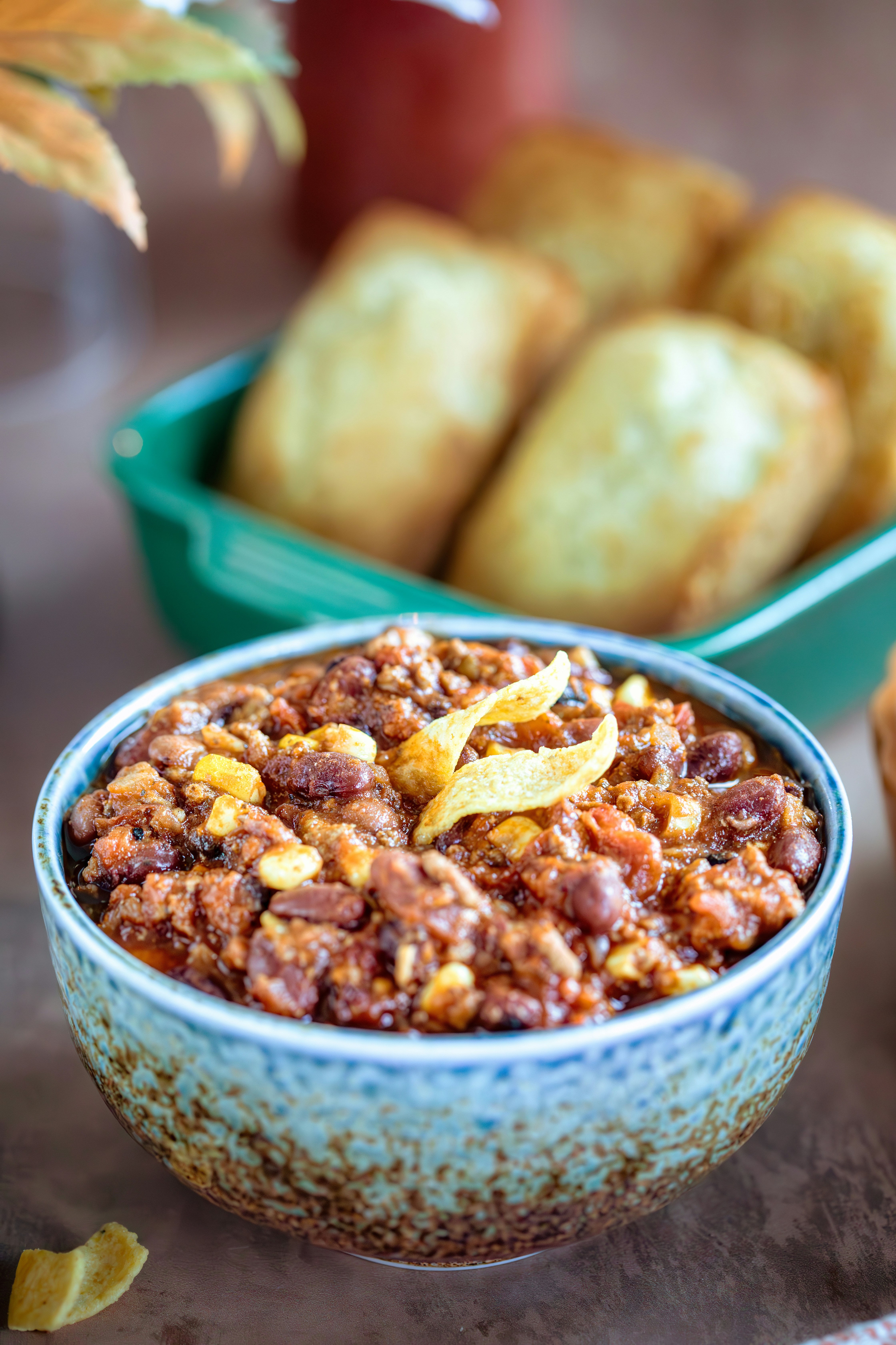 A bowl of chili next to some muffins