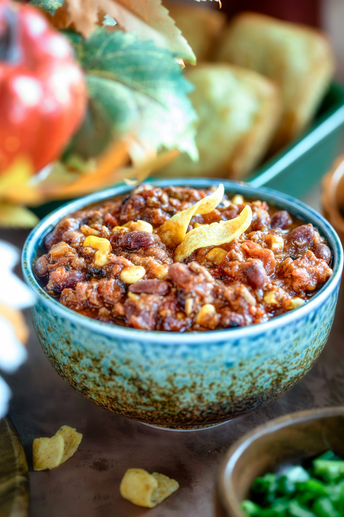 A bowl of beef, bean and corn chili topped with tortilla chips