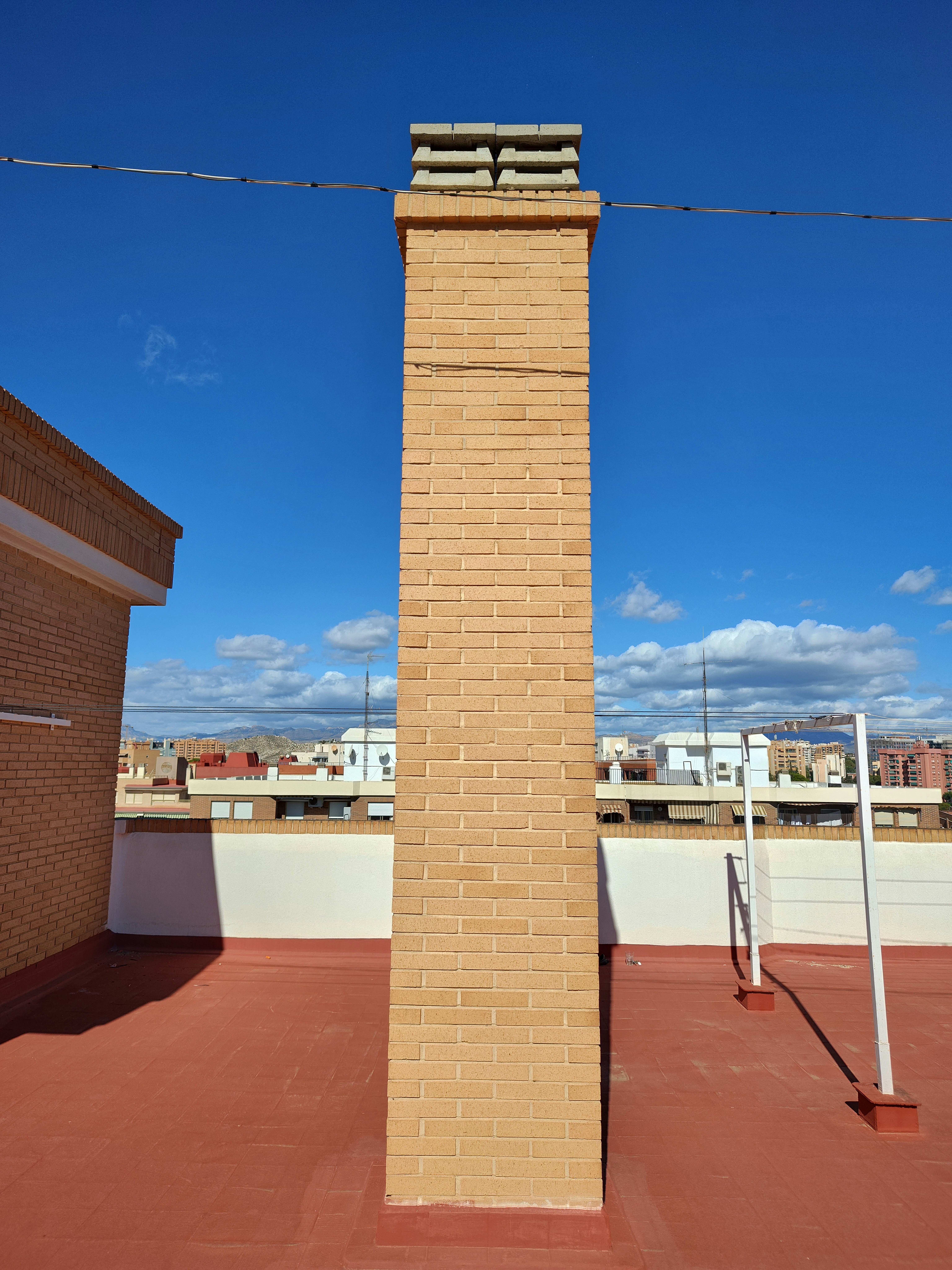 Residential brick chimney on rooftop, clear sky