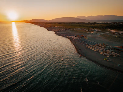 The sun is setting over a beach with umbrellas