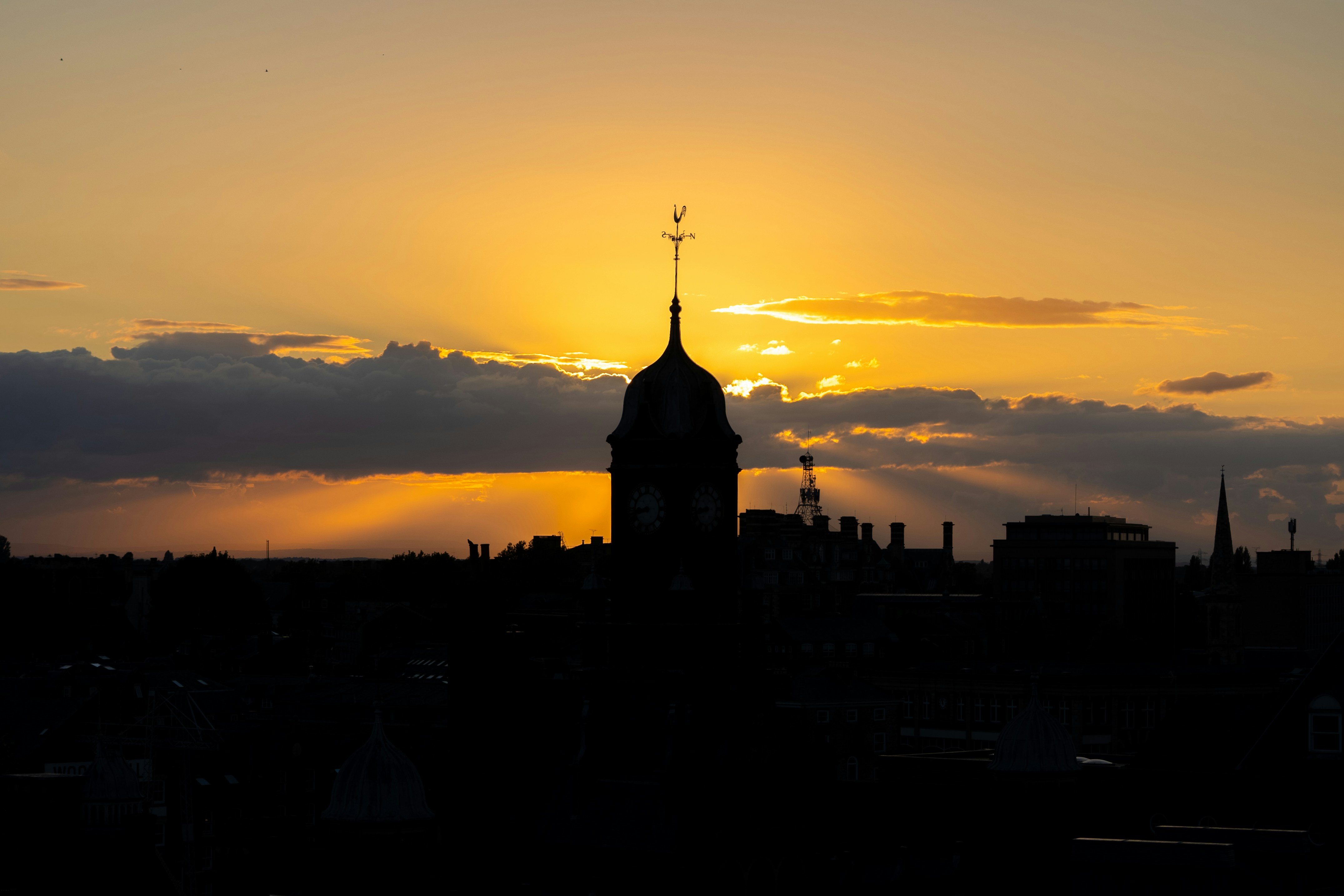 The sun is setting over a city with a clock tower