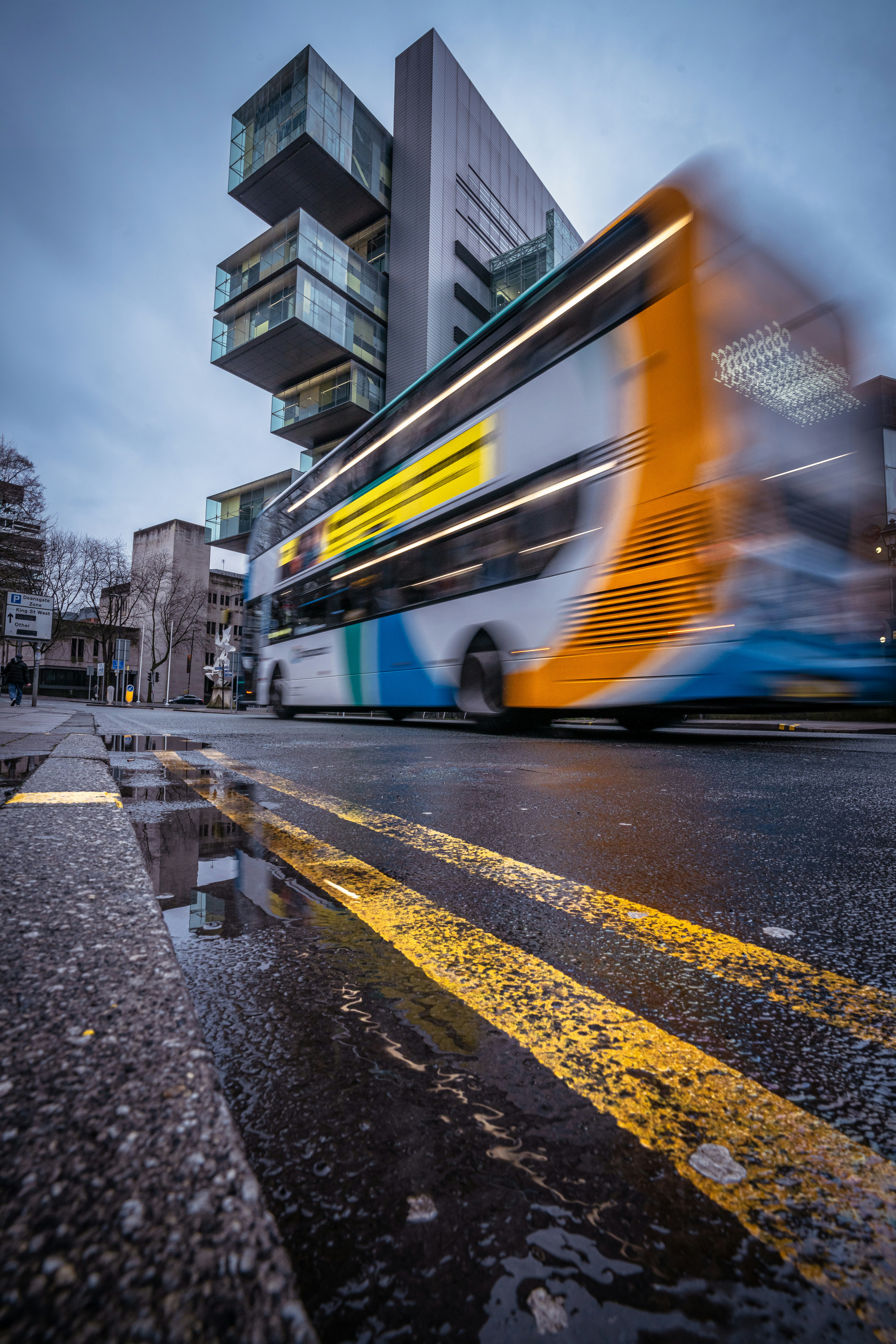 A double decker bus driving past a tall building