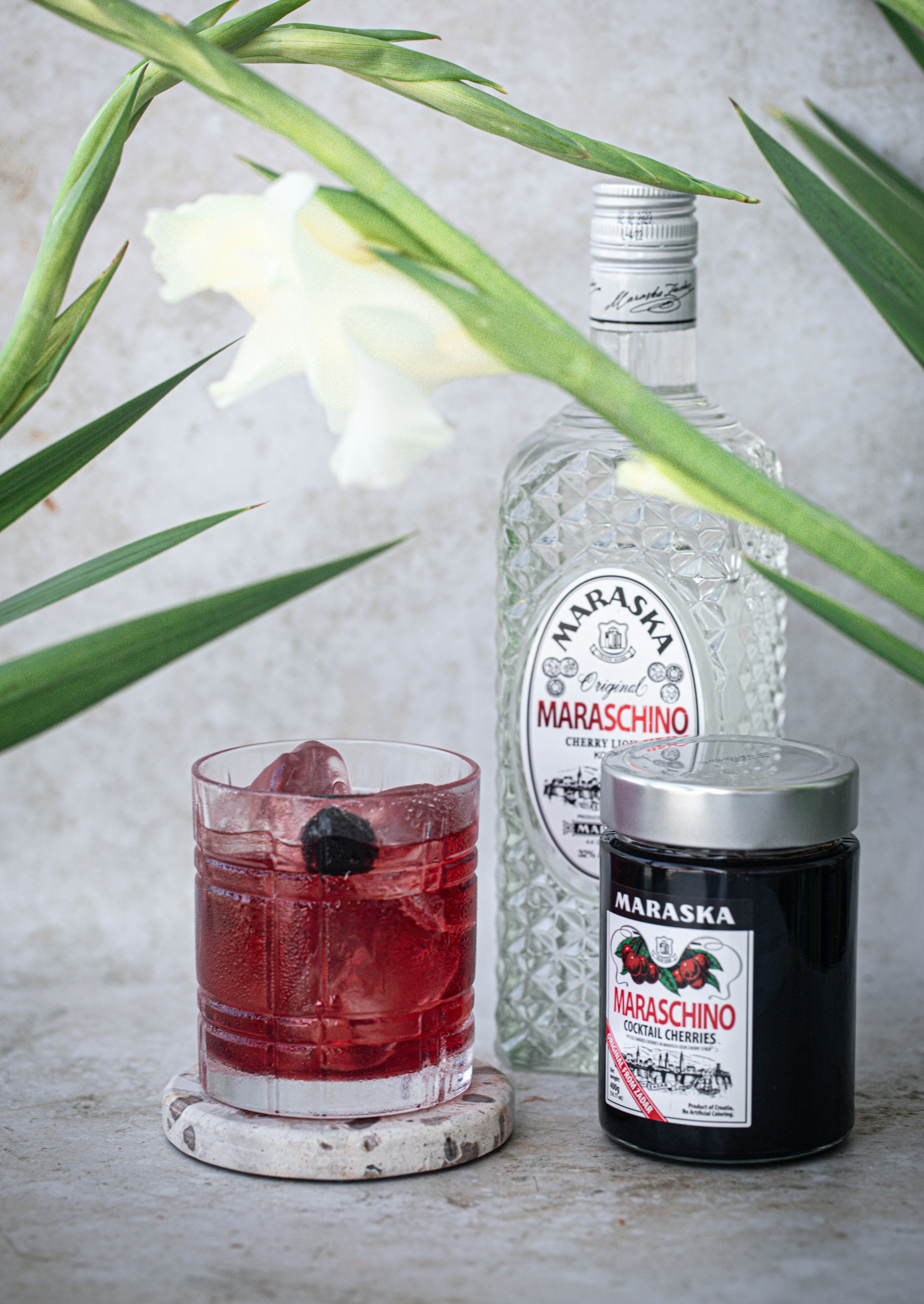 A bottle of vodka next to a glass with a black berry garnish