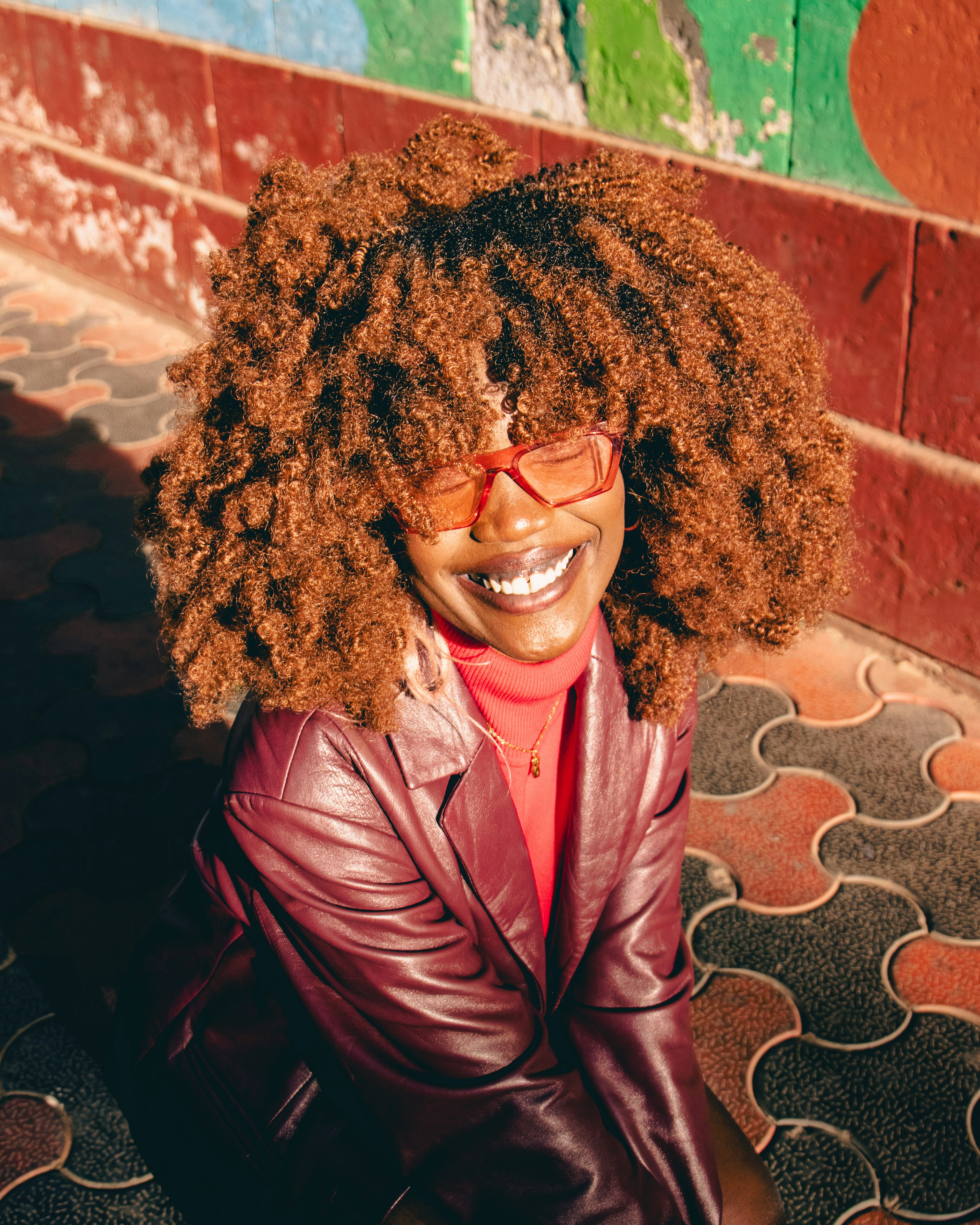 A woman sitting on the ground wearing a leather jacket