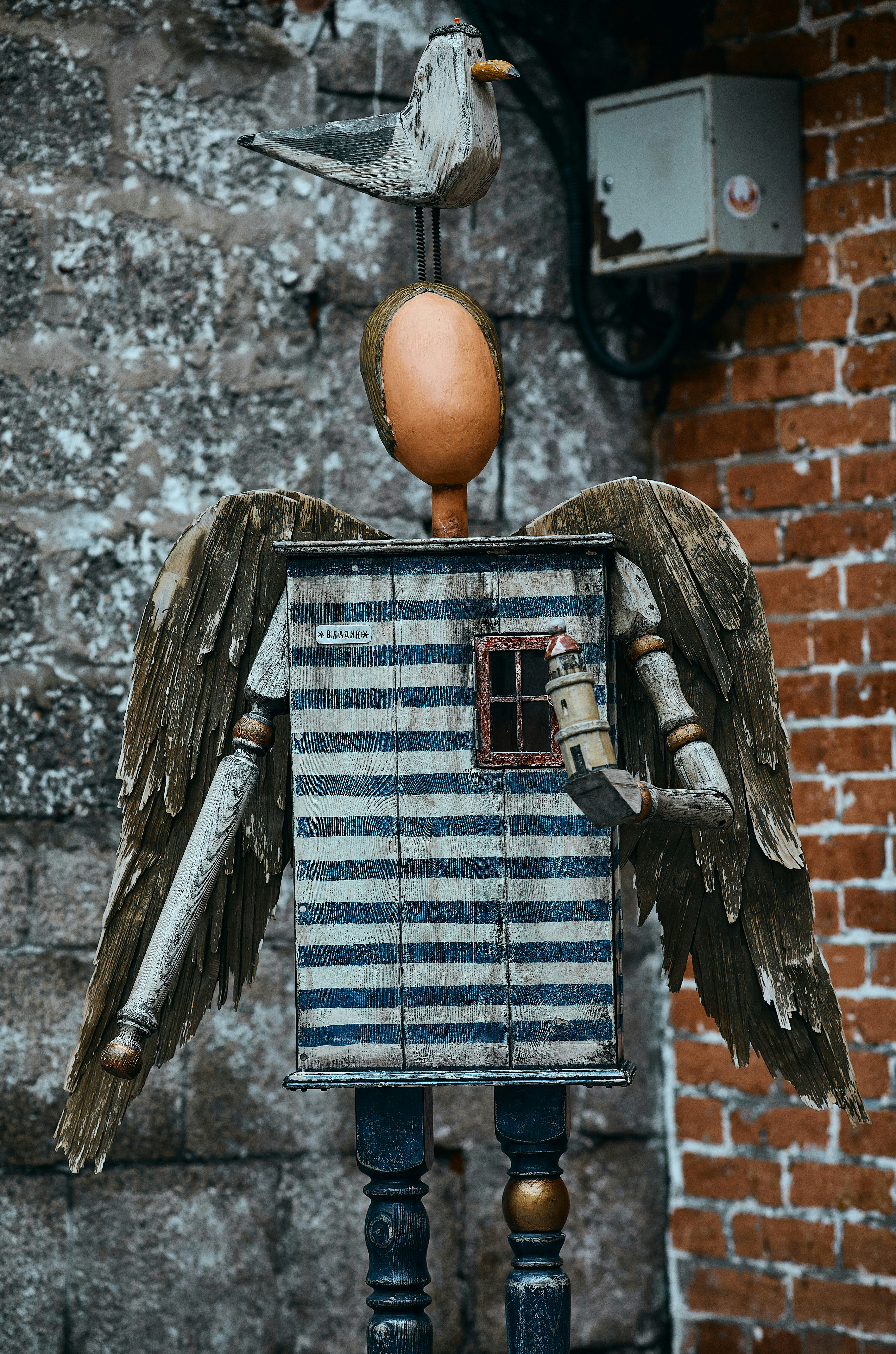 A wooden doll with a bird on top of it