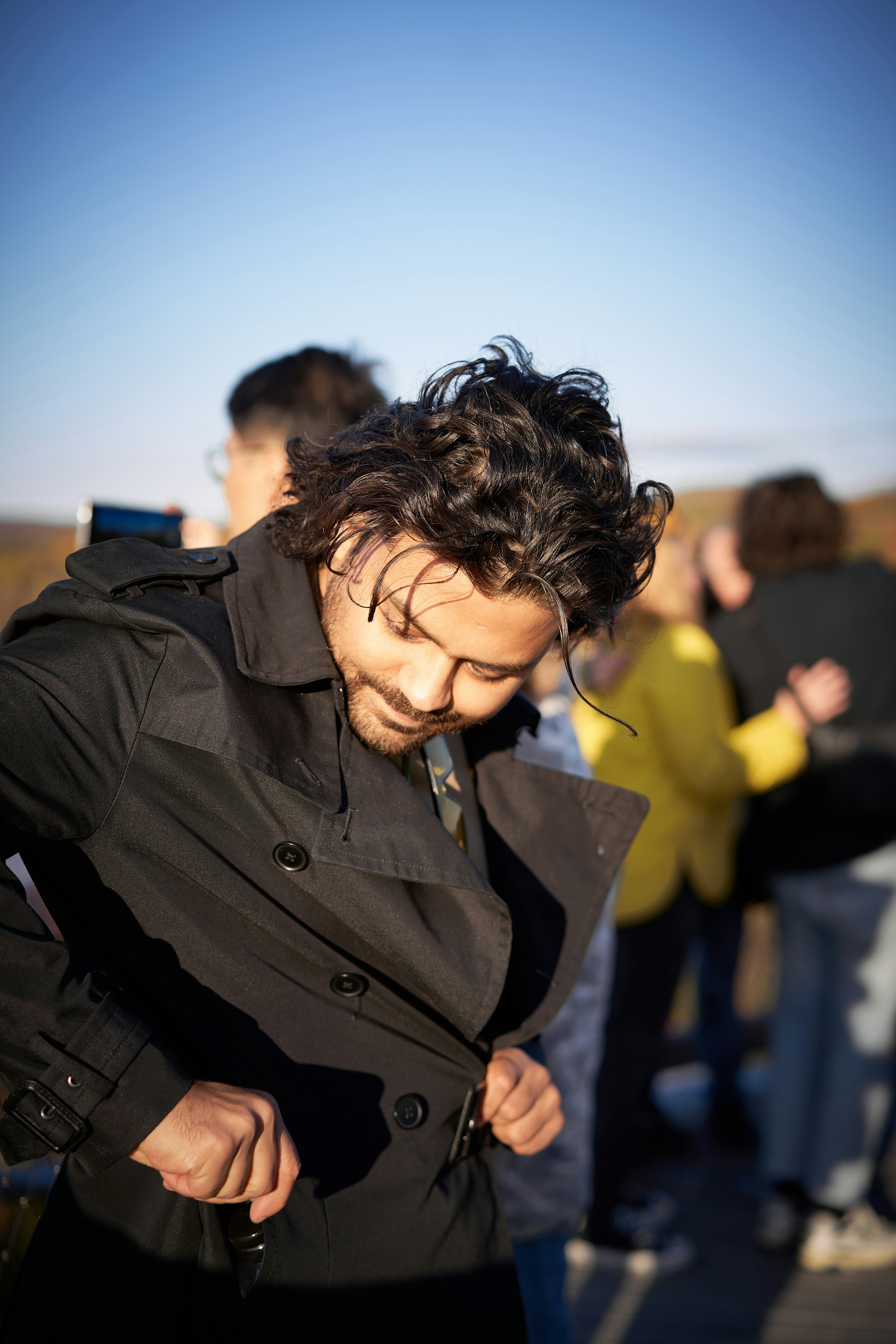 A man in a trench coat looking at his cell phone