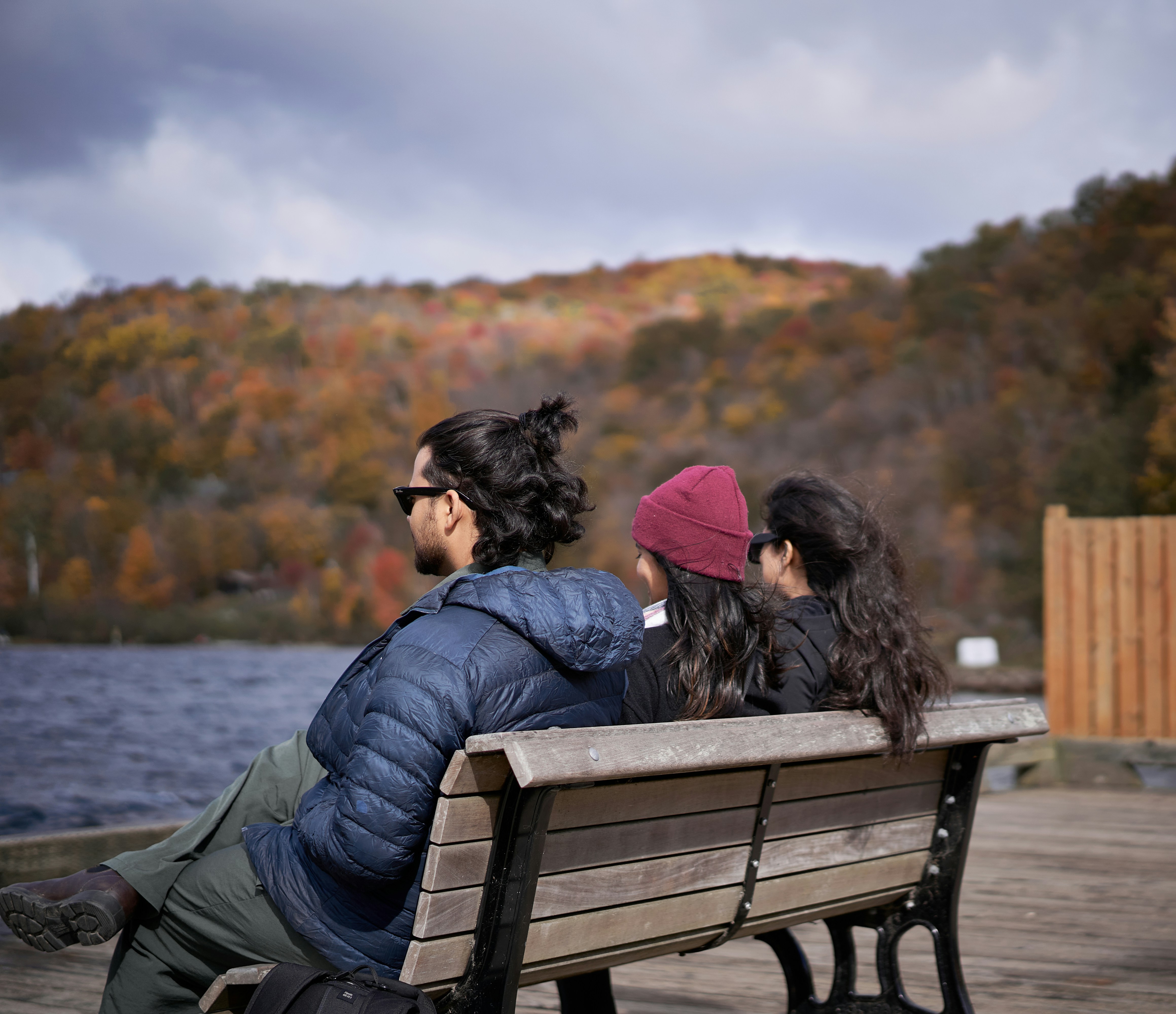 Three people sitting on a bench near a body of water