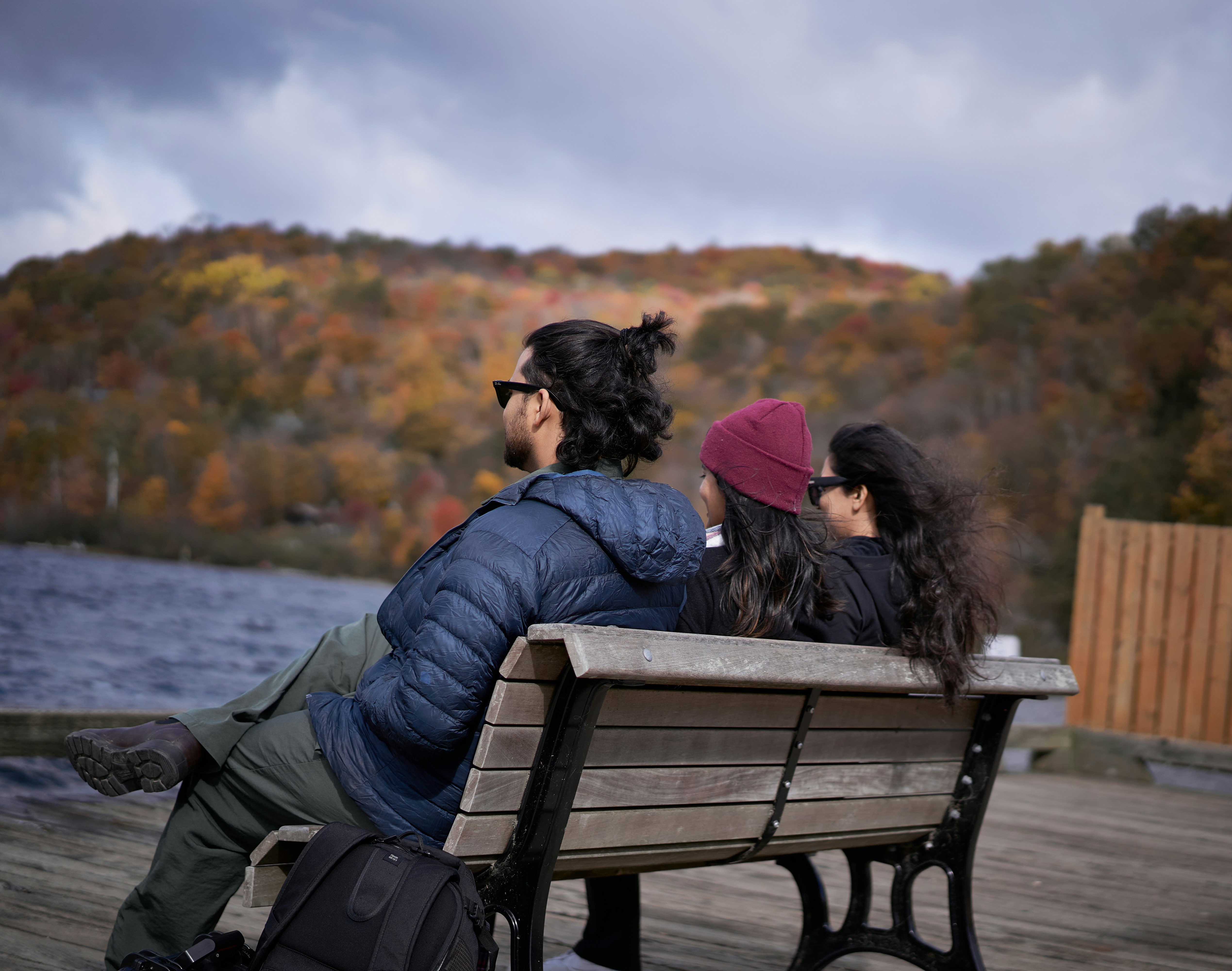 A couple of people sitting on top of a wooden bench