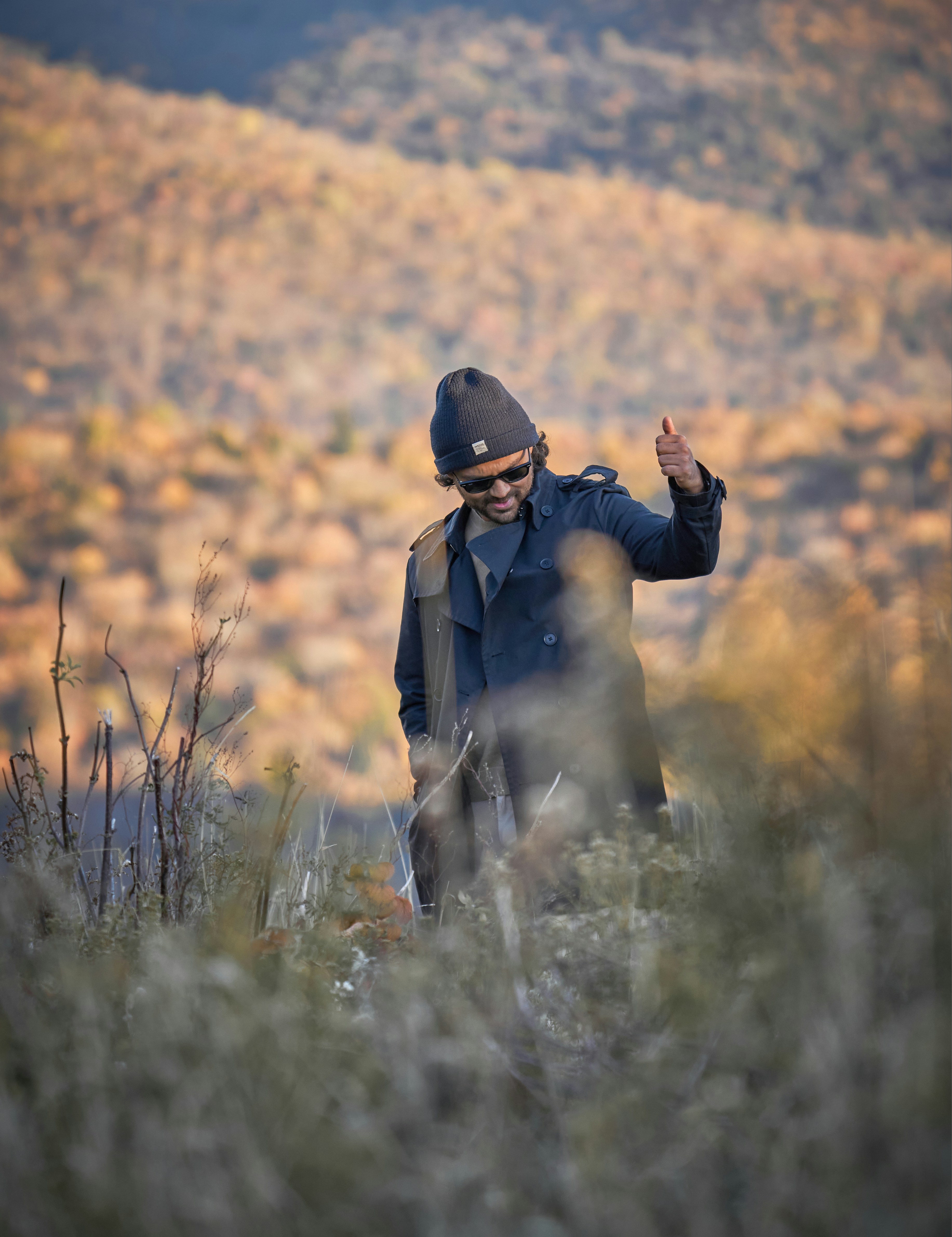 A man walking through a field with a hat on