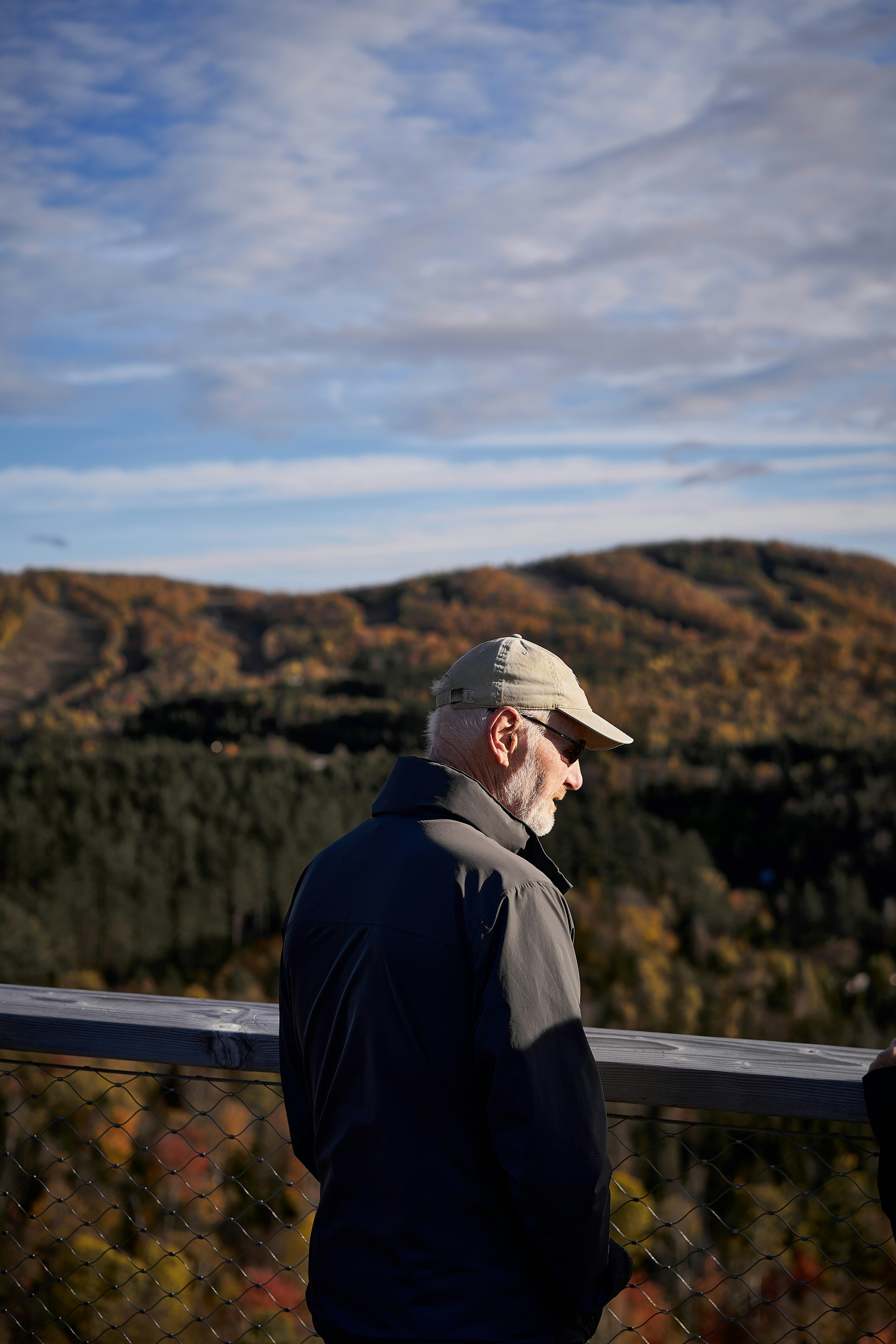 A man standing on top of a hill next to a forest