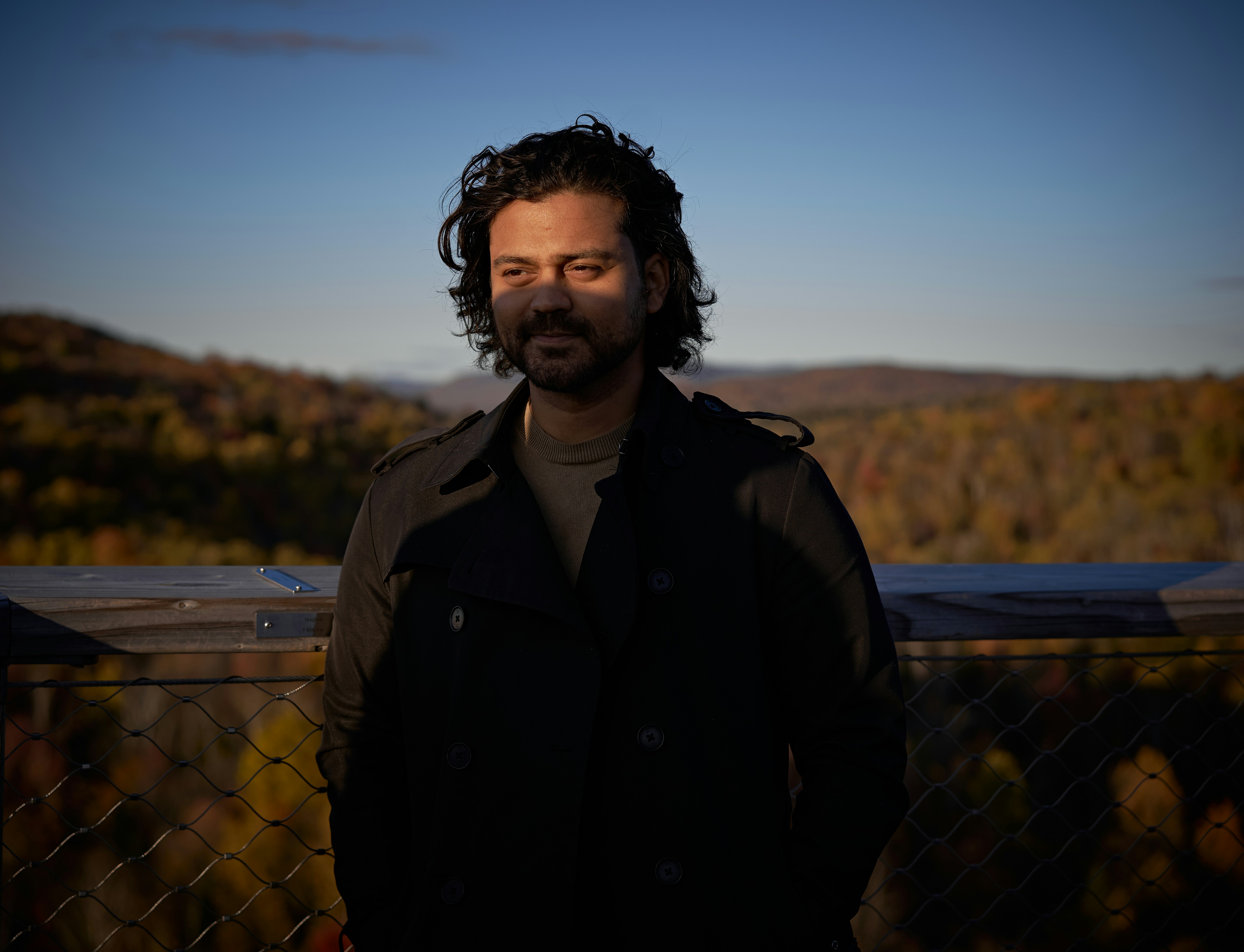 A man standing in front of a chain link fence