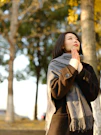 A woman standing in front of a tree with her hands together