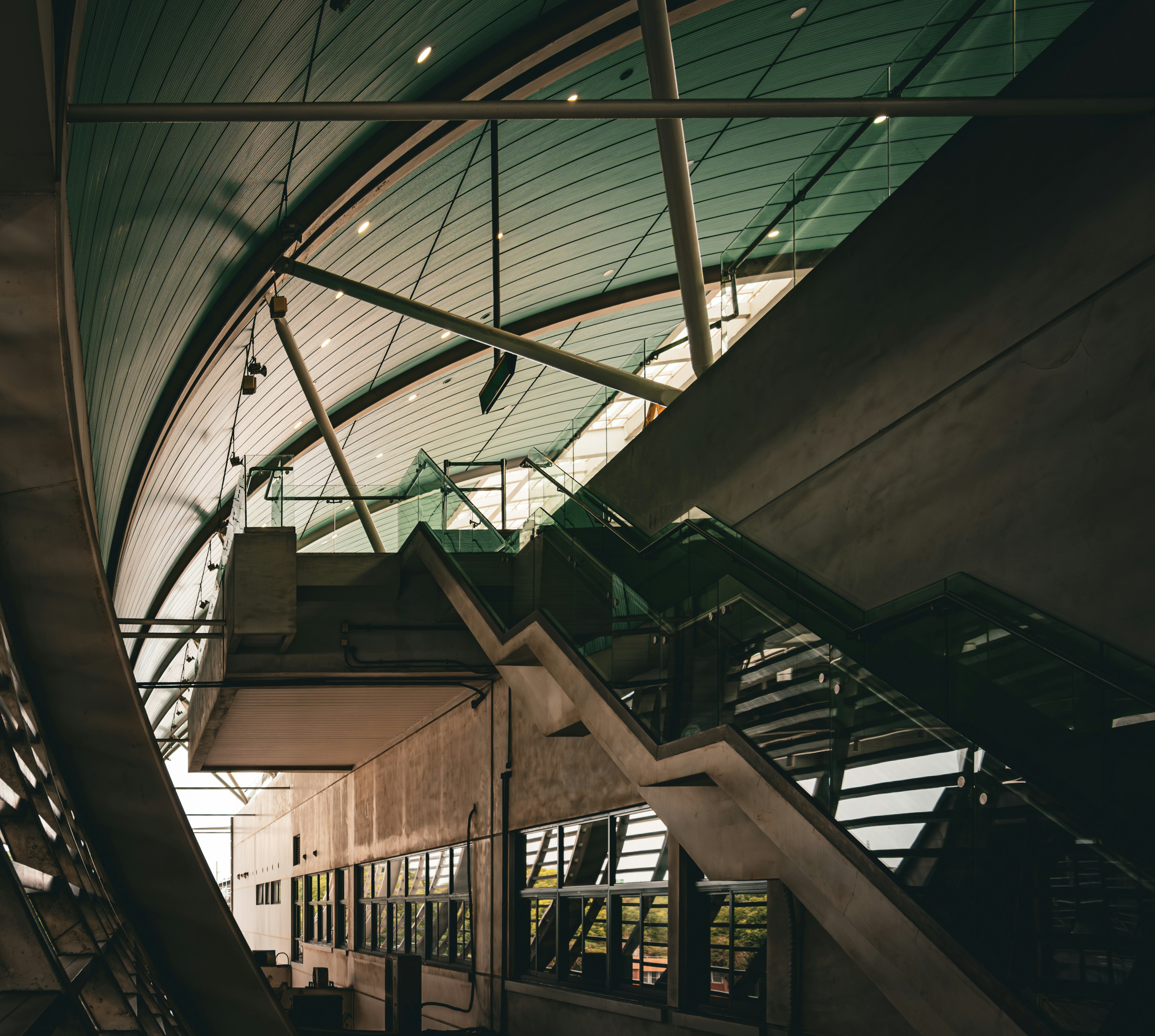 An escalator inside of a building with a glass roof