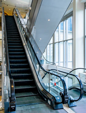 An escalator in a large building with lots of windows