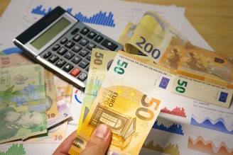 A person holding a bunch of money next to a calculator
