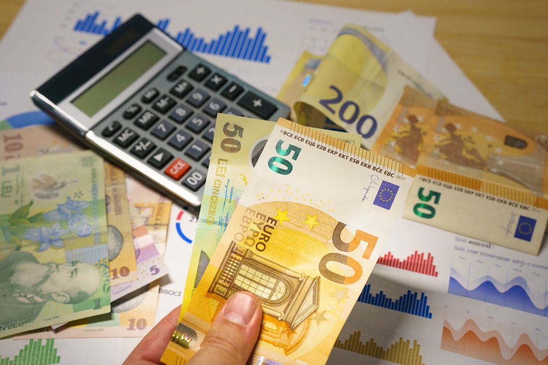 A person holding a bunch of money next to a calculator, euro lei banknotes