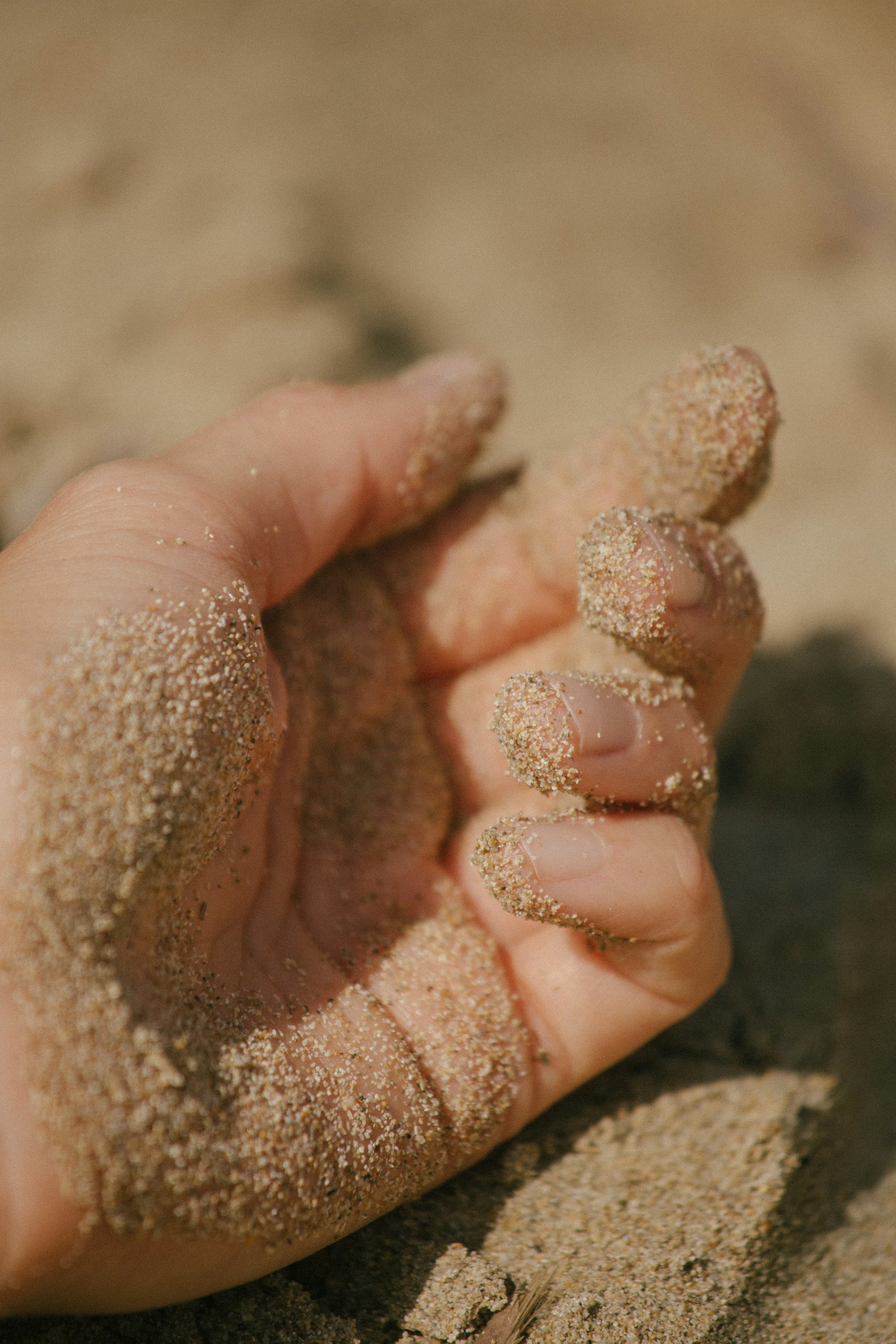 A hand holding sand in the sand on a beach