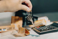 A person holding a house key in front of a calculator