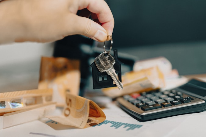 A person holding a house key in front of a calculator, showing the rent versus buy comparison Las Vegas renters are weighing