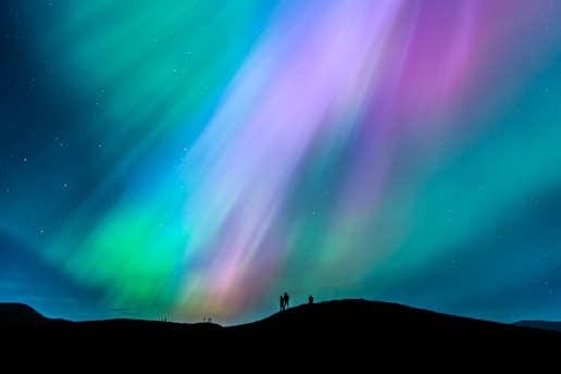 A person standing on a hill watching the aurora bore