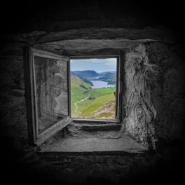 A window in a stone wall with a view of a lake