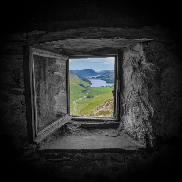 A window in a stone wall with a view of a lake