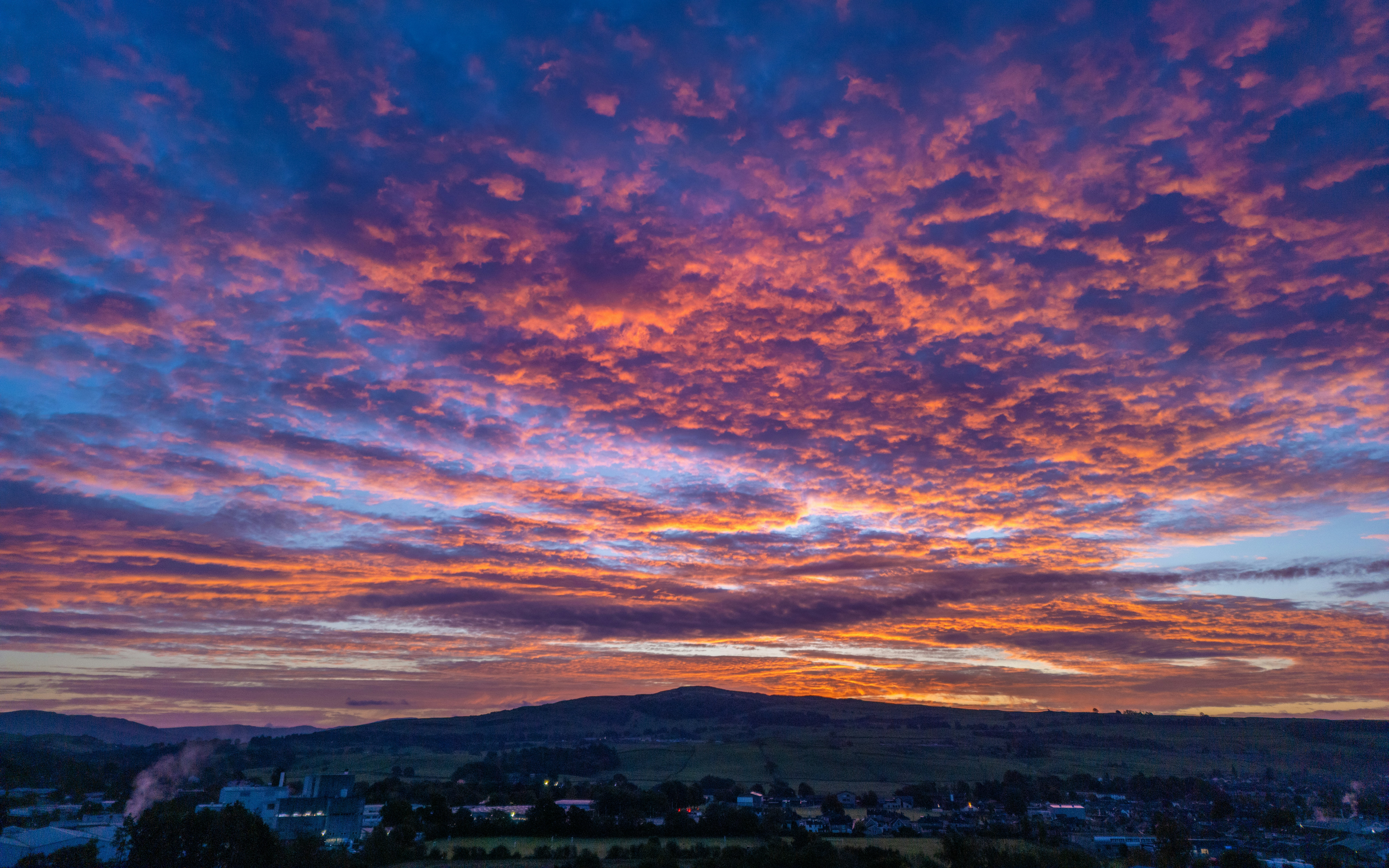 山を背景にした街に沈む色とりどりの夕日の写真 – Unsplashの壁紙の
