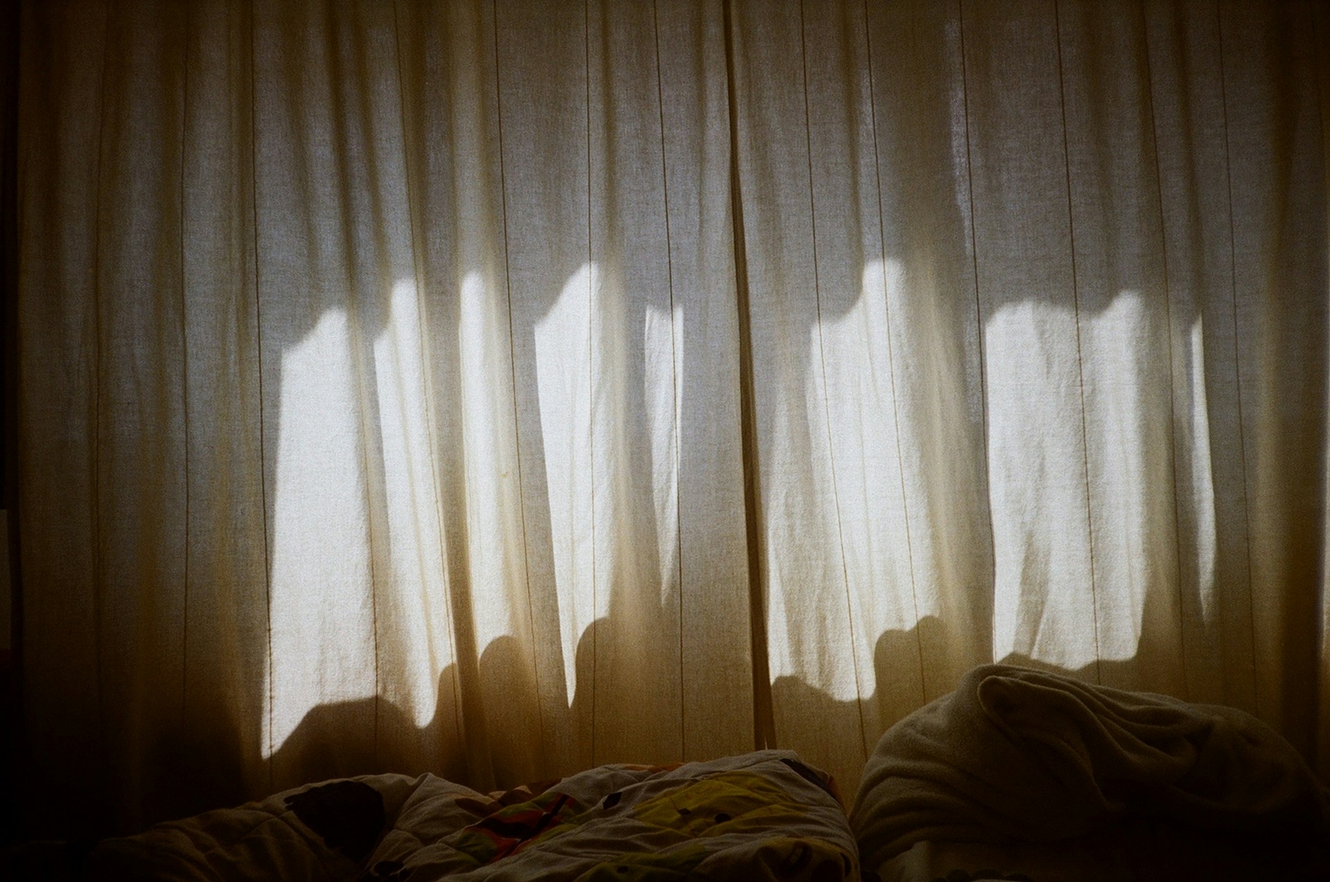 A bedroom with a bed and a curtained window