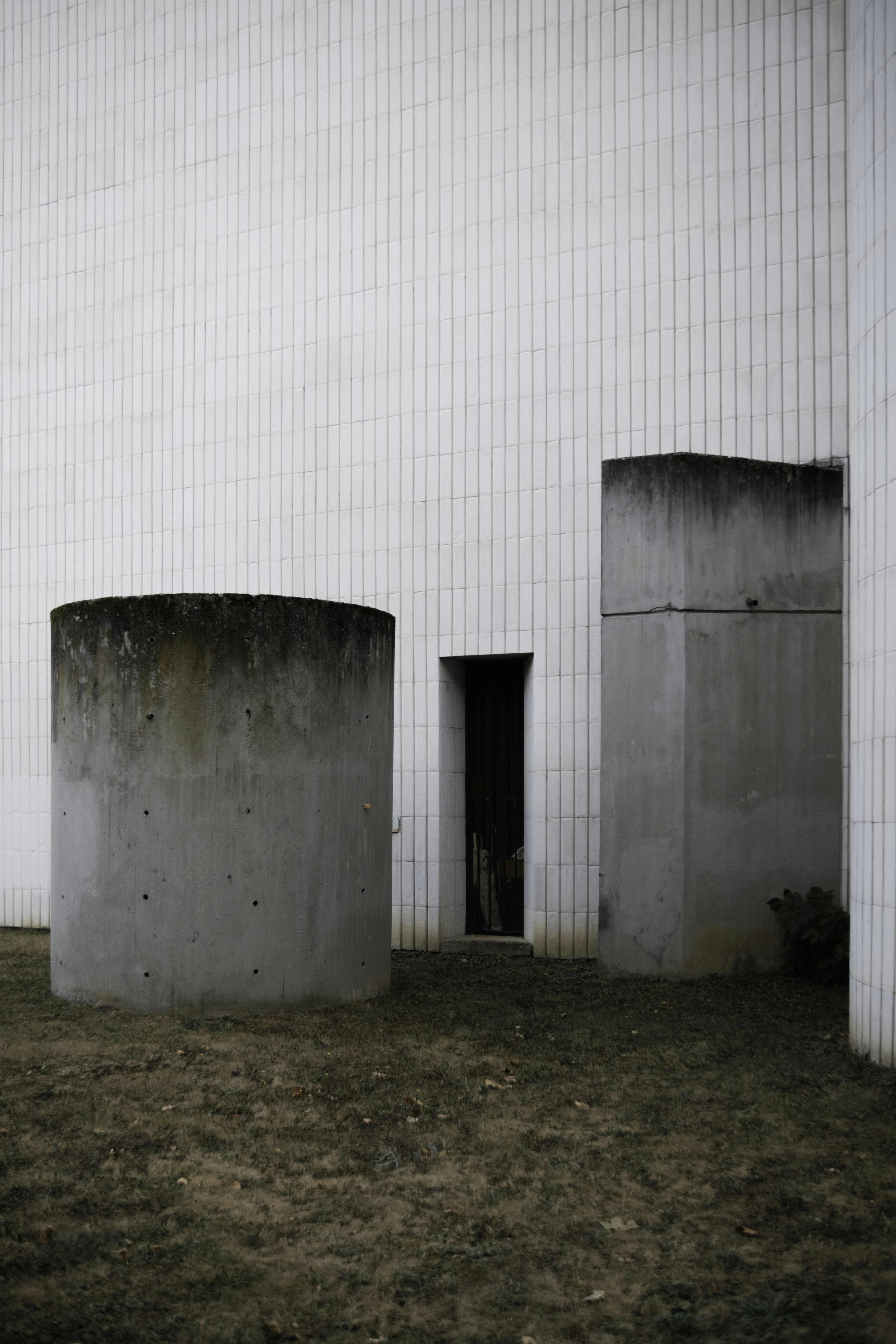 A white building with three cement pillars in front of it