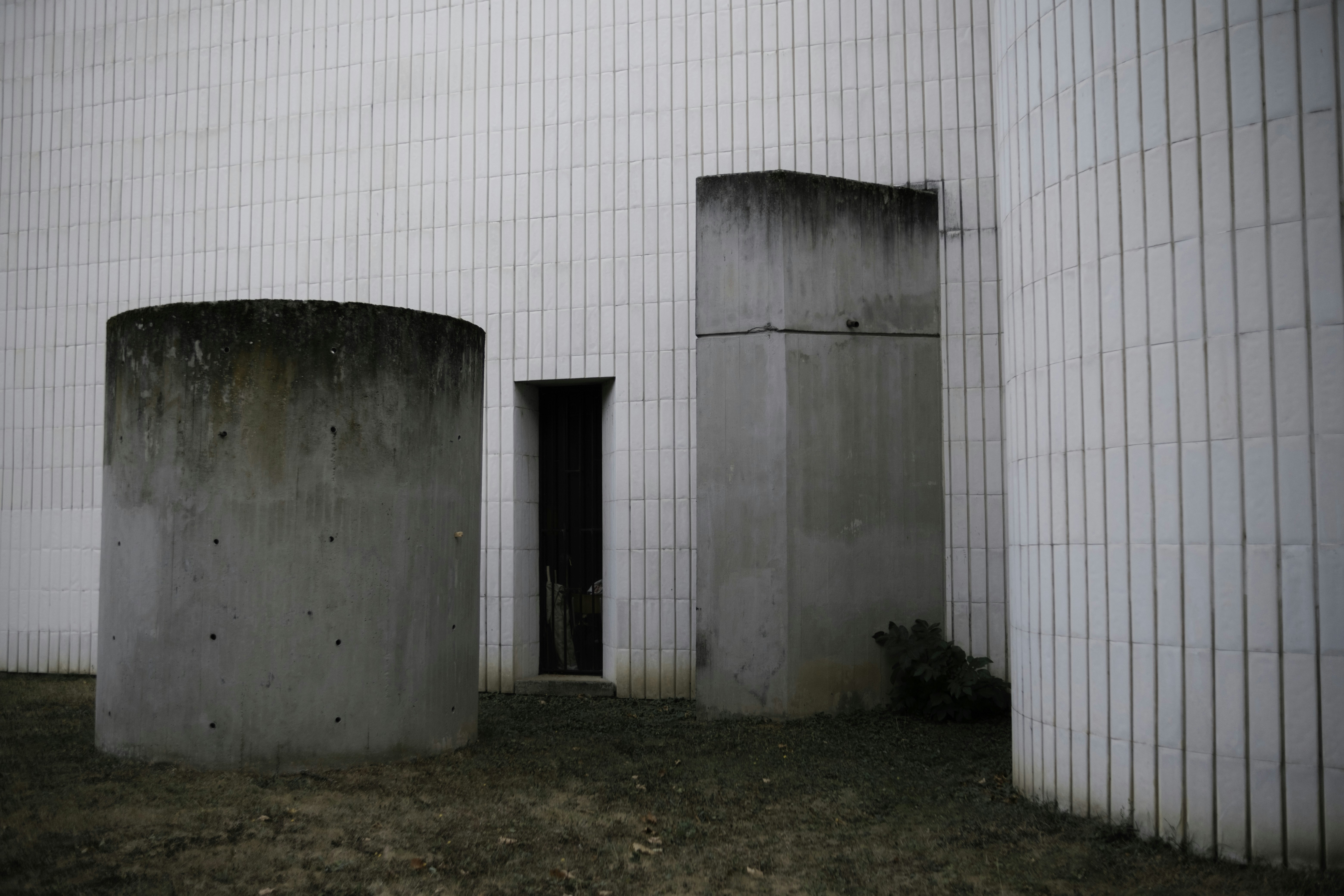 A white building with two cement tanks in front of it