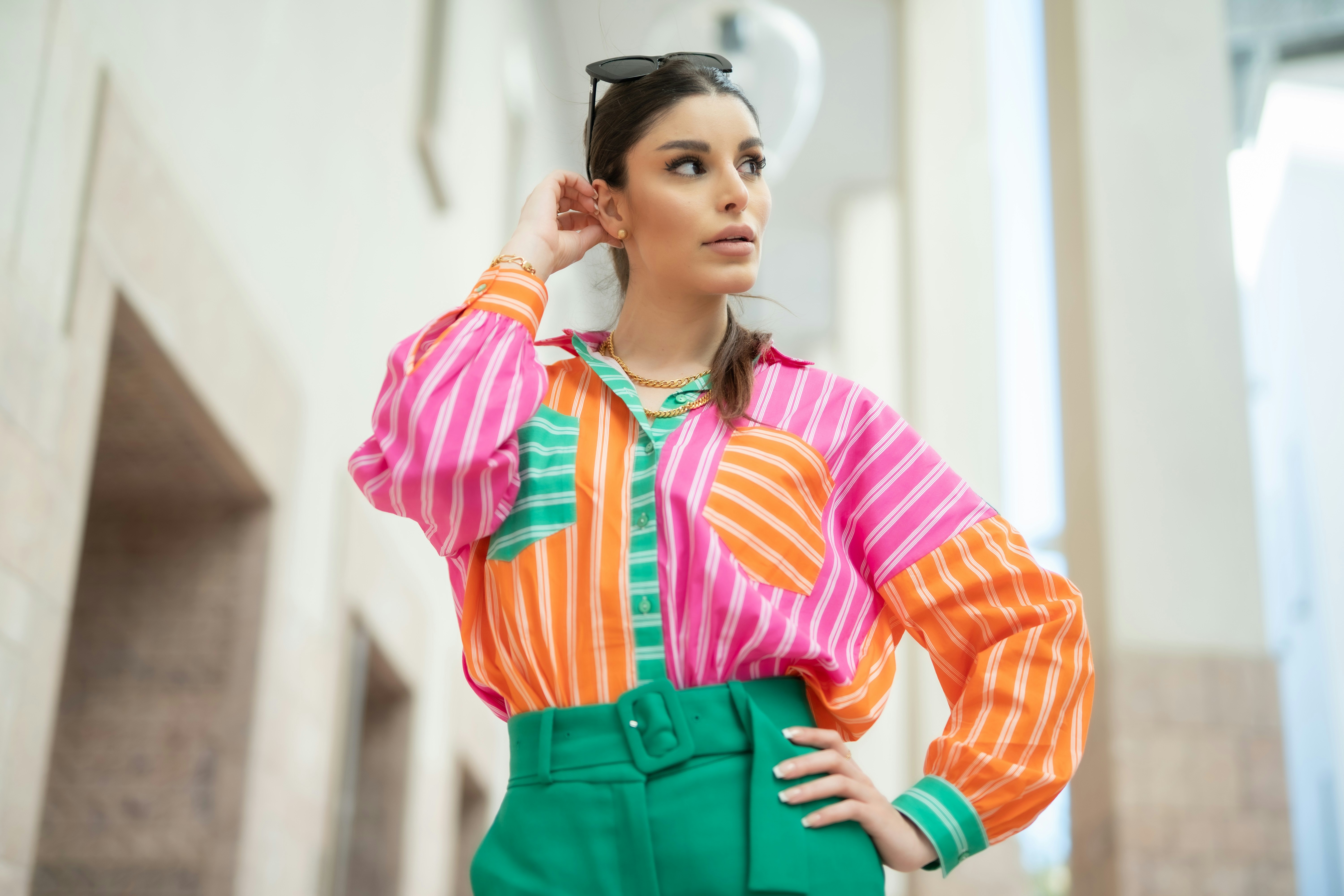 A woman wearing a colorful shirt and green pants