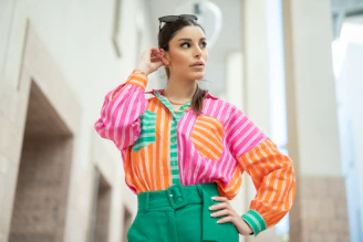 A woman wearing a colorful shirt and green pants