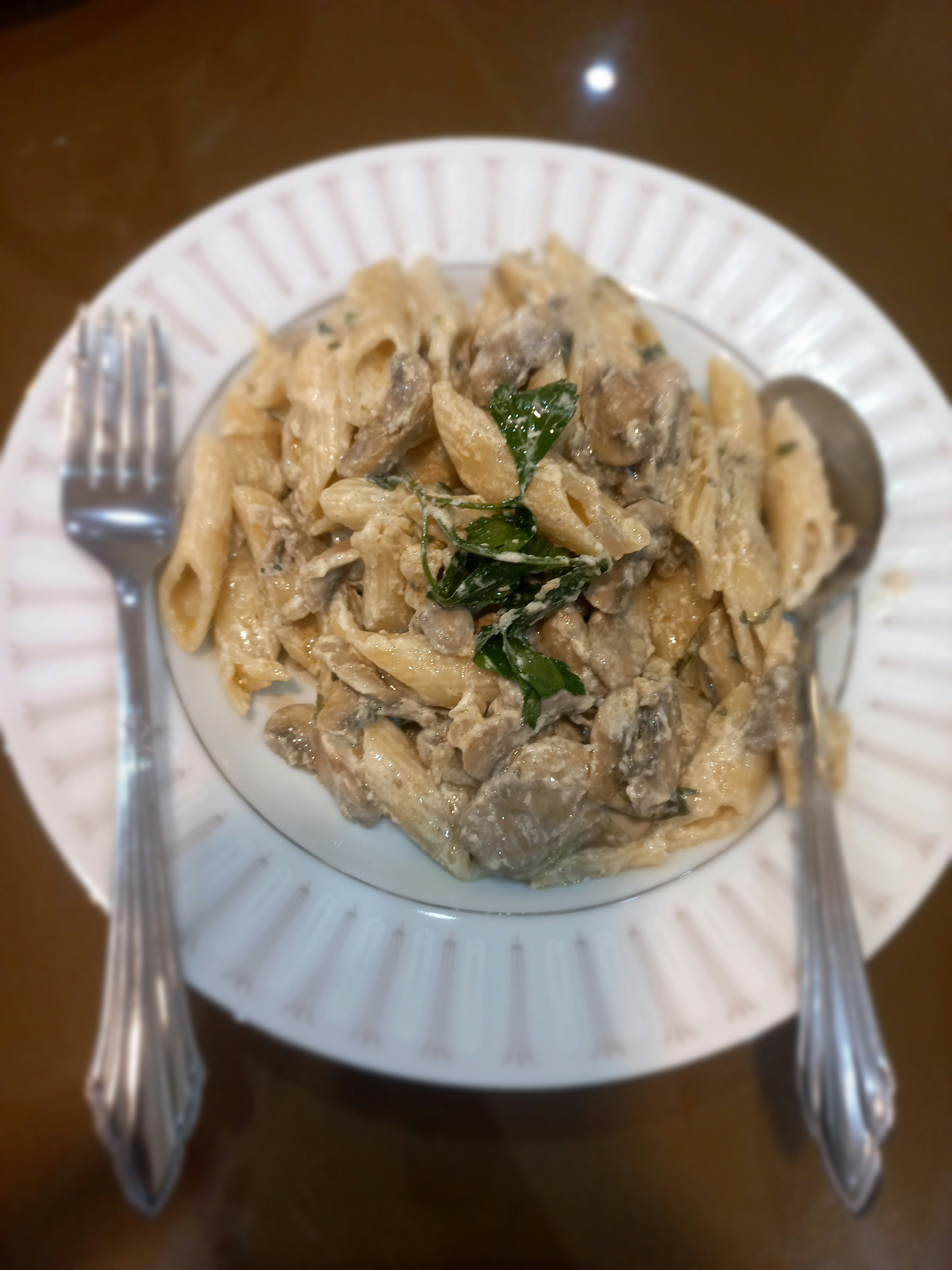 Pasta dish with creamy sauce and fresh herbs on dark slate, candlelight ambiance