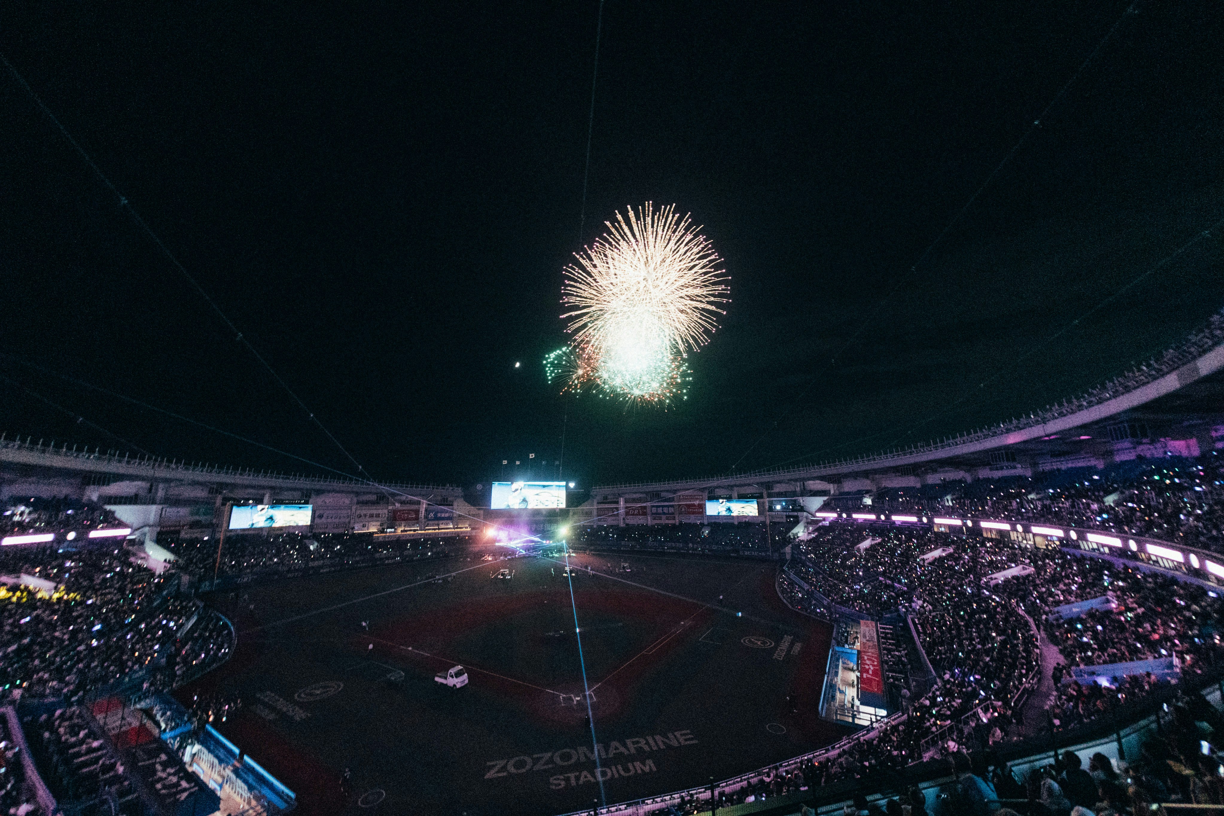 Celebración nocturna de alto nivel con fuegos artificiales y luces de colores sobre estadio lleno de espectadores