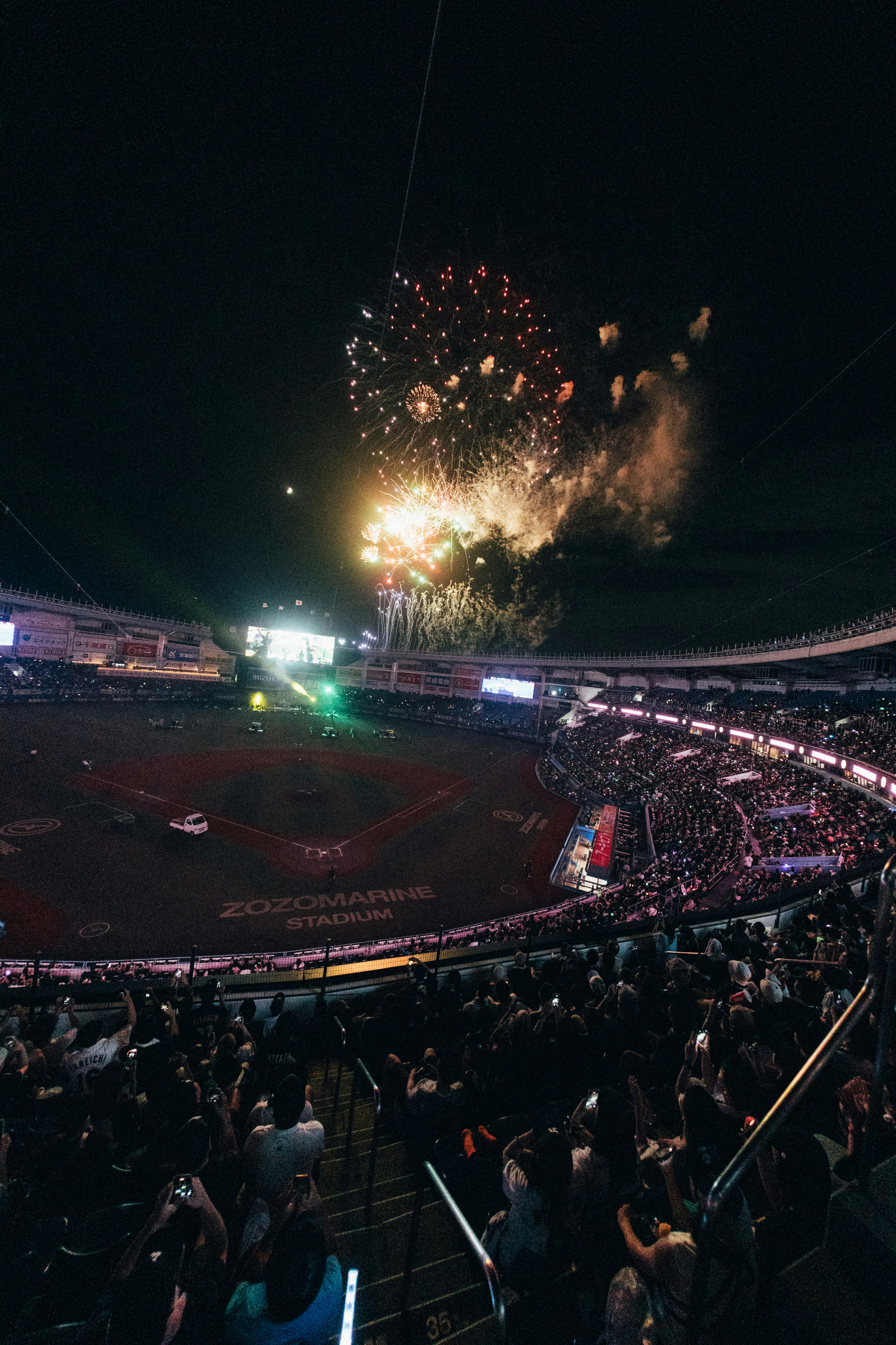 Sebuah stadion bisbol yang dipenuhi dengan banyak orang yang menonton kembang api