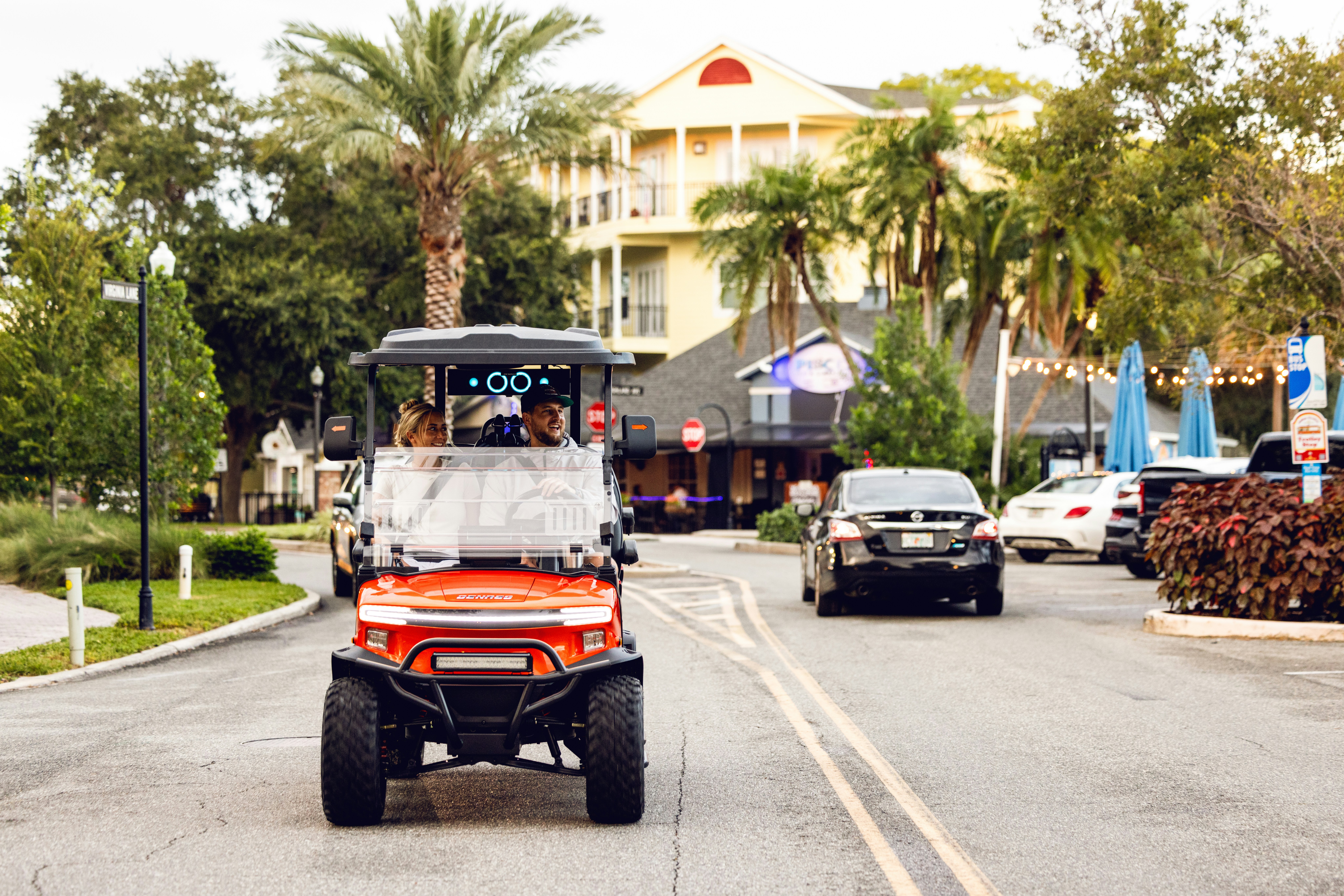 A red golf cart driving down a street