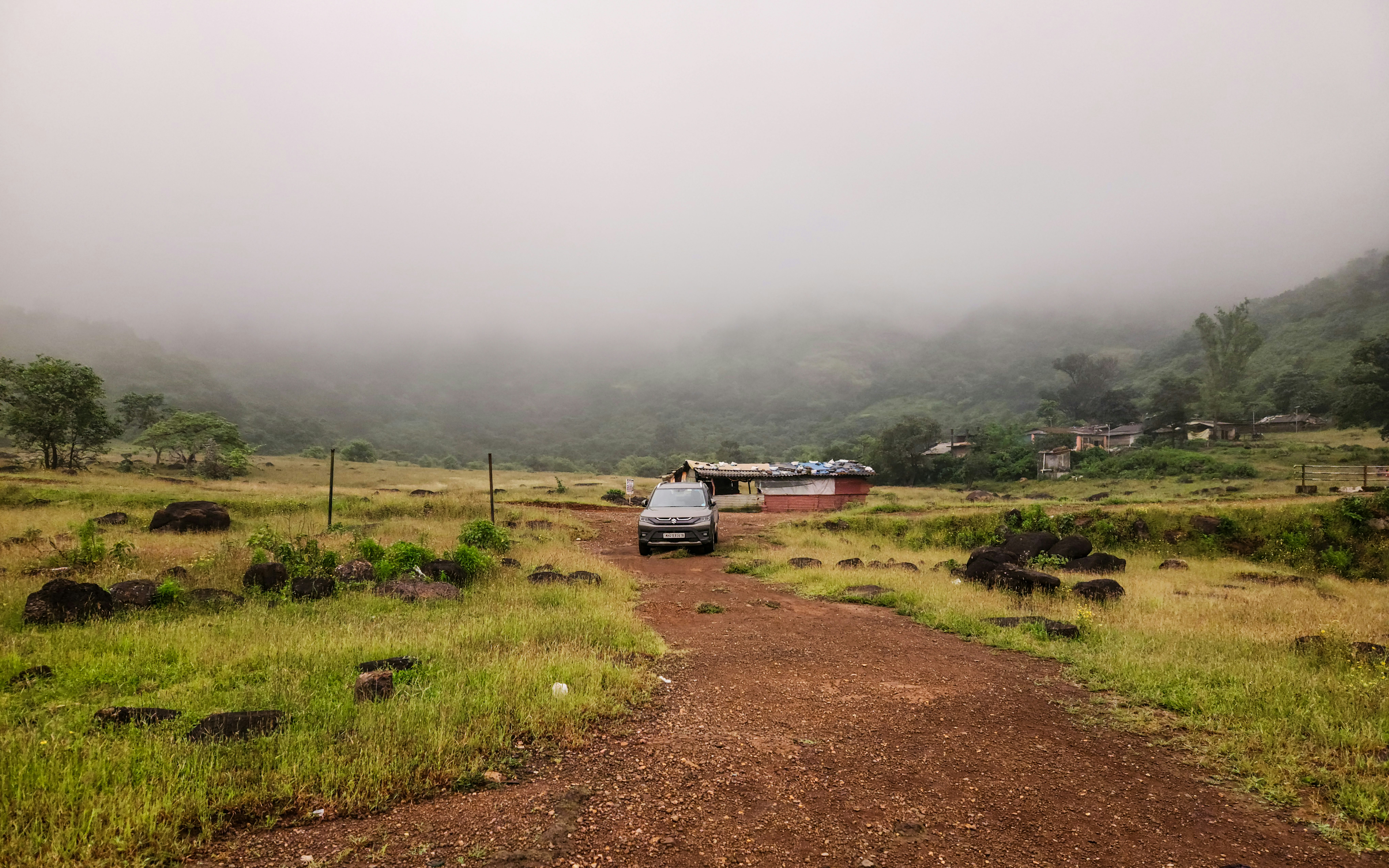 A car parked on a dirt road in the middle of a field