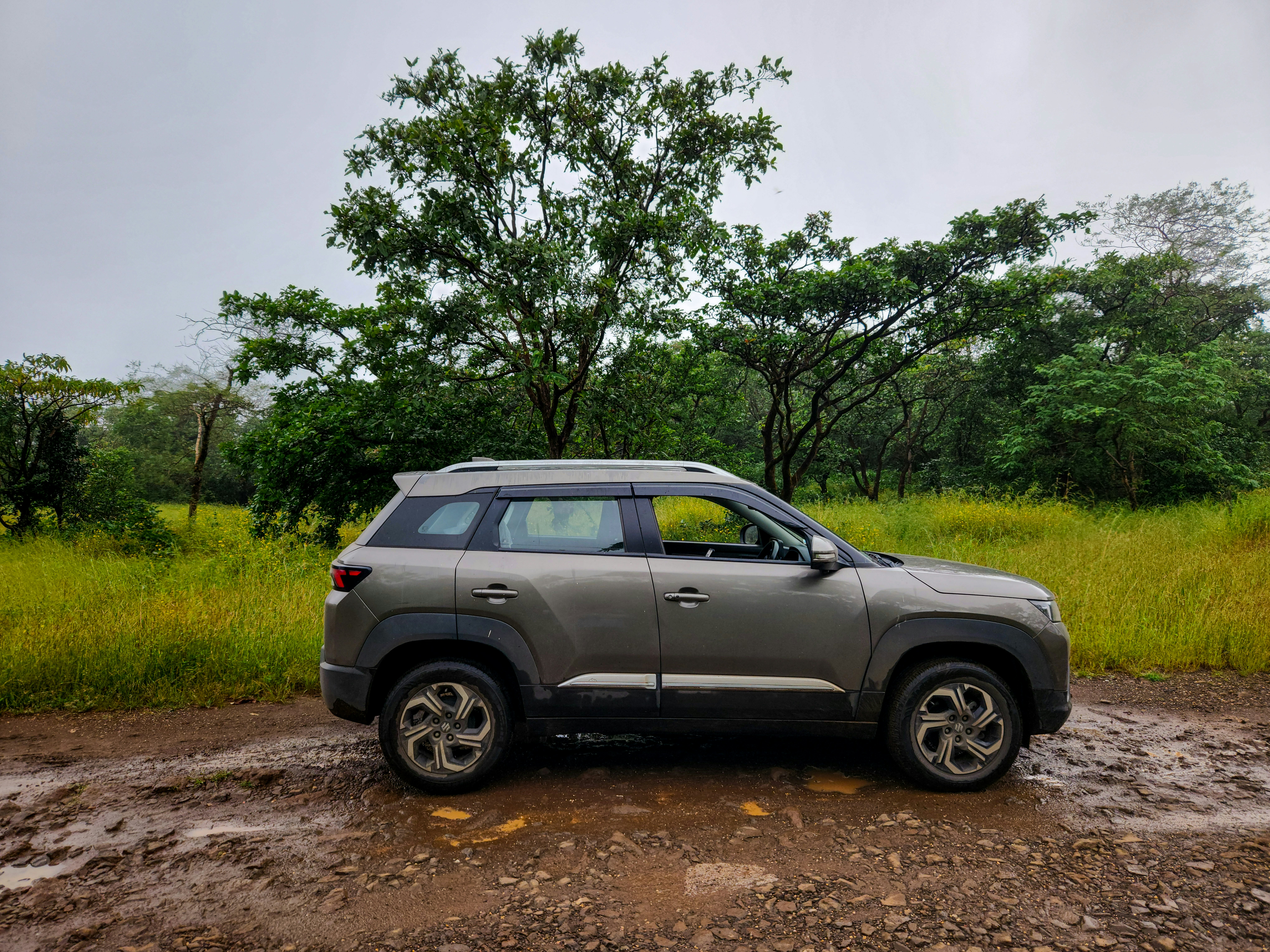A car parked on a muddy road in the middle of a field