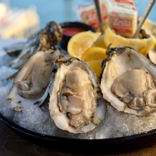A plate of oysters with lemon wedges and ketchup