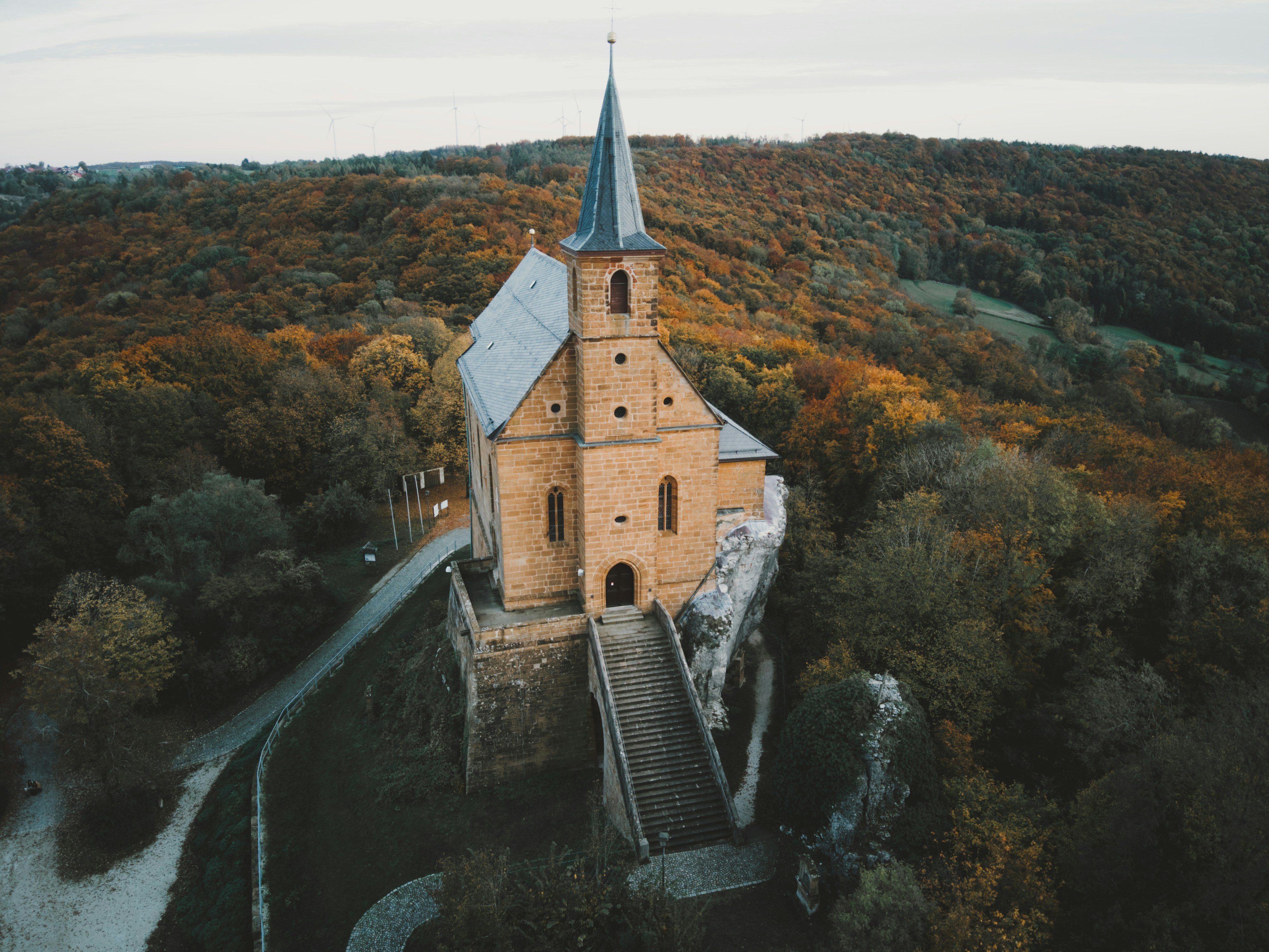 An aerial view of a church in the middle of a forest