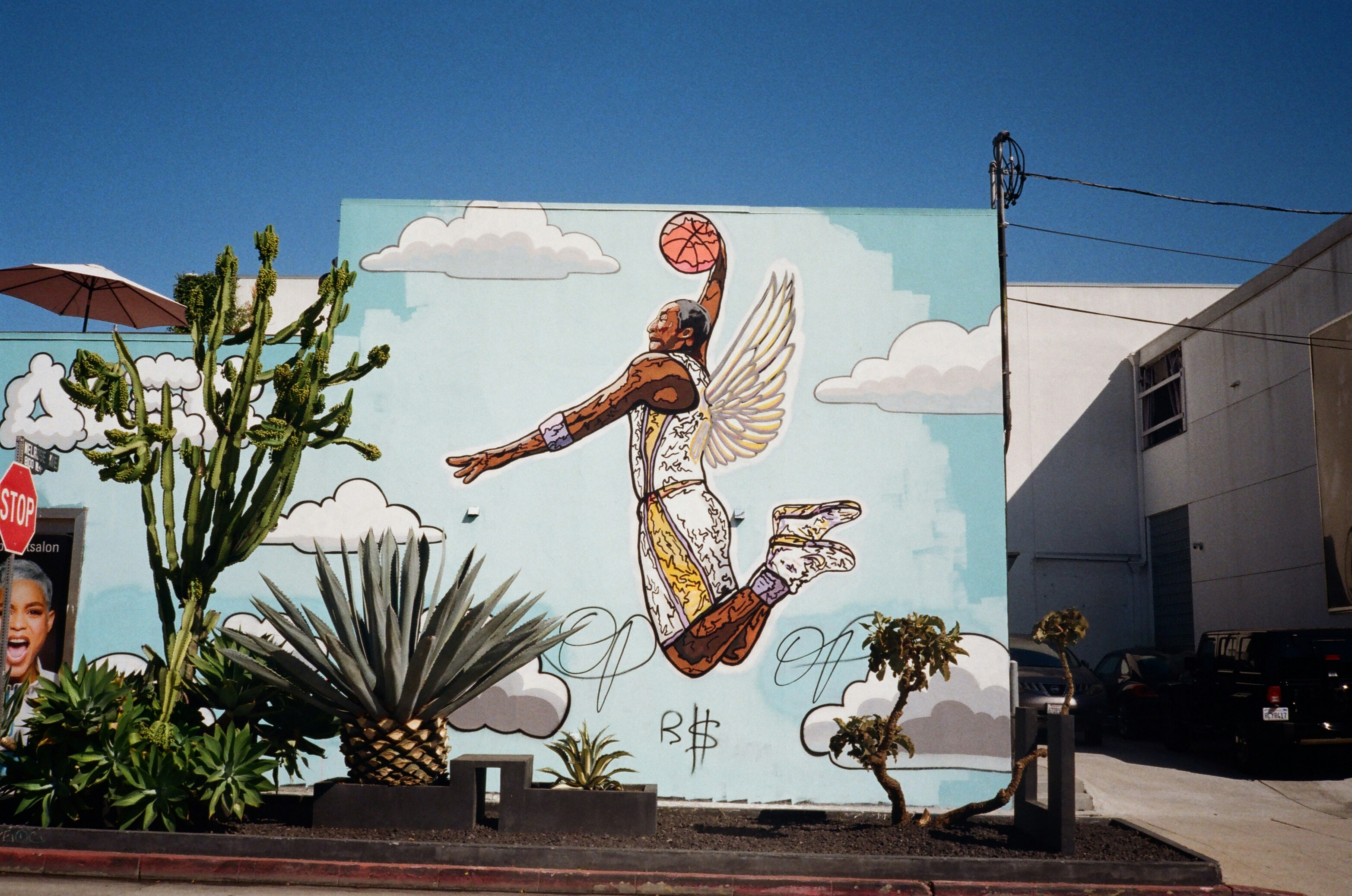 A mural of a basketball player is painted on the side of a building