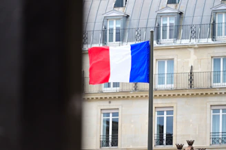 A flag flying in front of a tall building