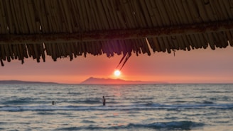 The sun is setting over the ocean and a beach