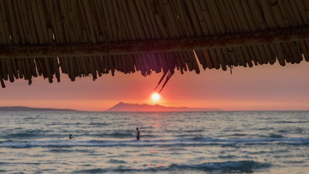 The sun is setting over the ocean and a beach