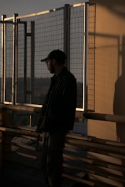 A man standing on top of a building next to a fence