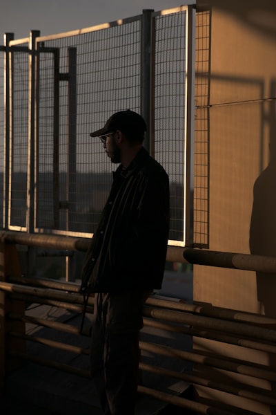 A man standing on top of a building next to a fence